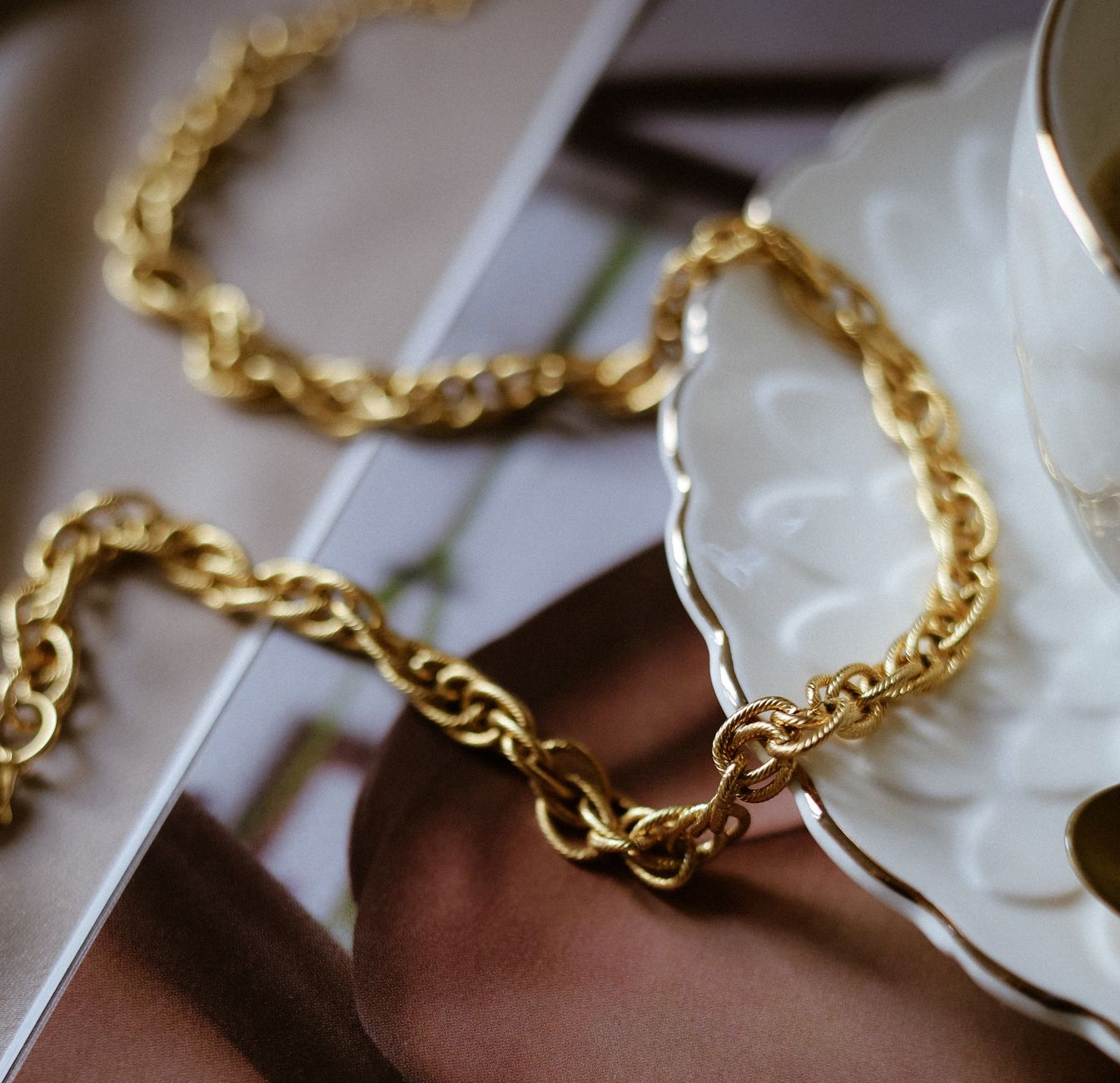 Close-up of a gold chain draped over a white plate, showcasing luxury jewelry.