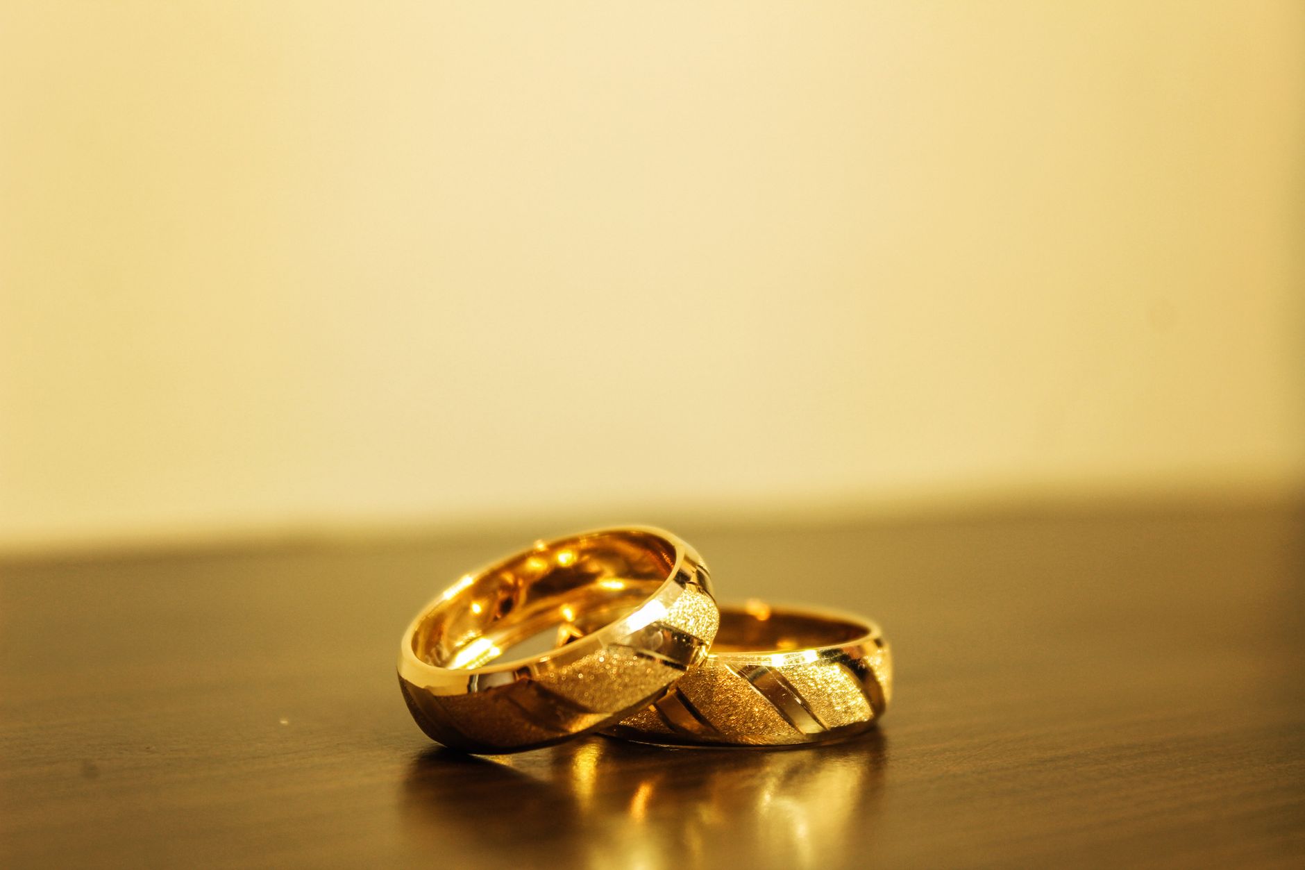 Close up of gold wedding rings symbolizing love and commitment on a wooden table.
