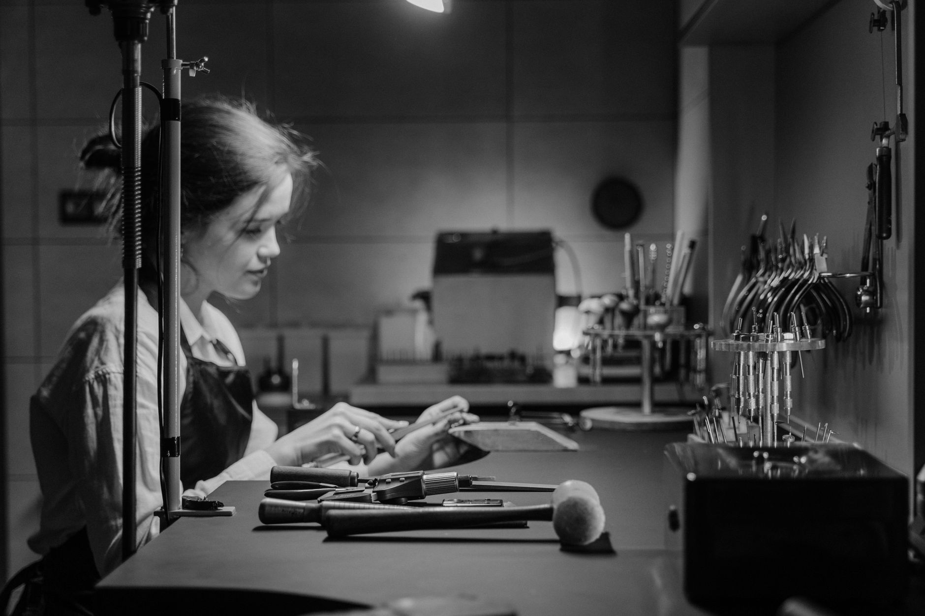 A skilled jeweler focuses on crafting jewelry at a well-equipped workshop bench.