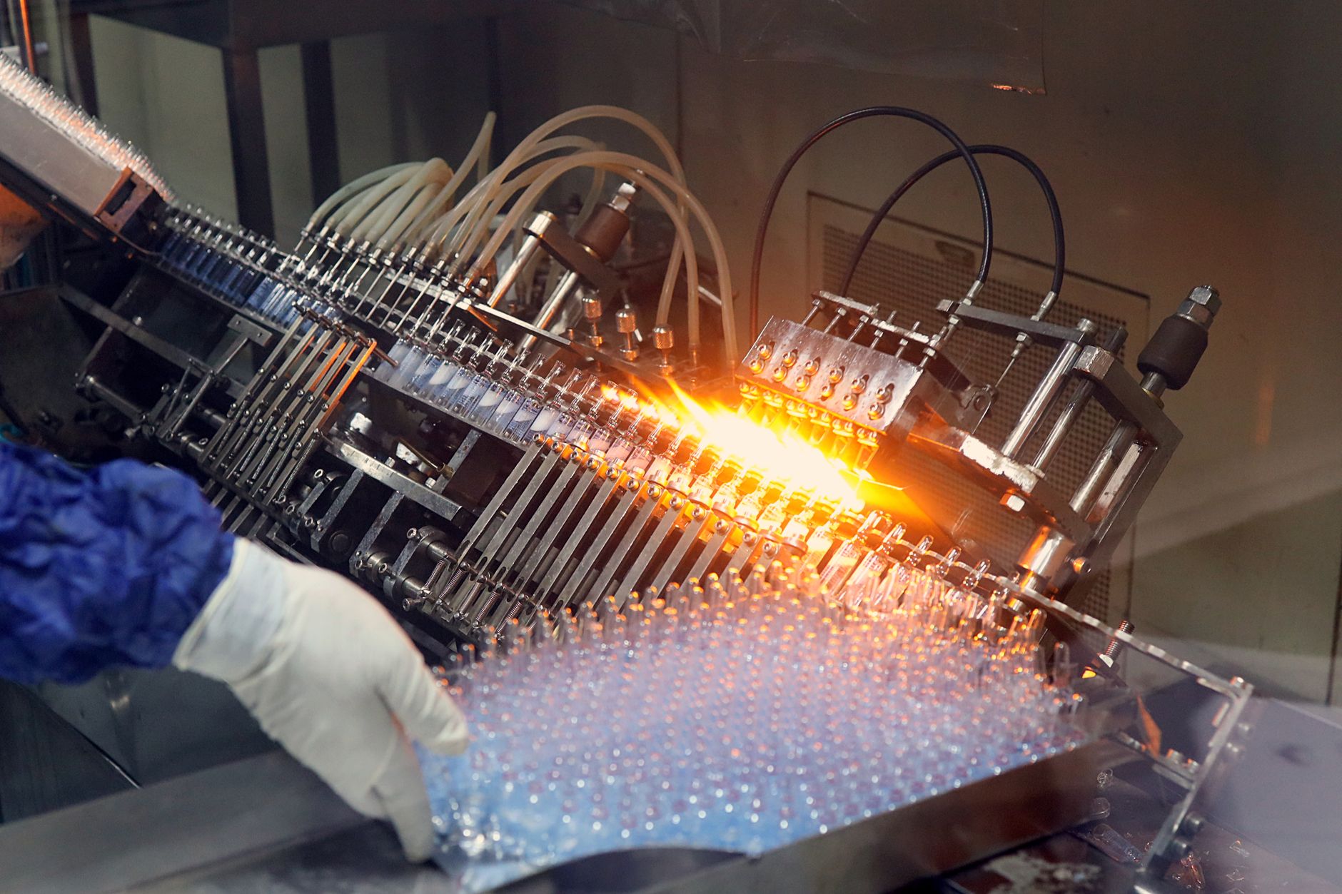 Close-up of ampoule filling and sealing in a pharmaceutical manufacturing line.
