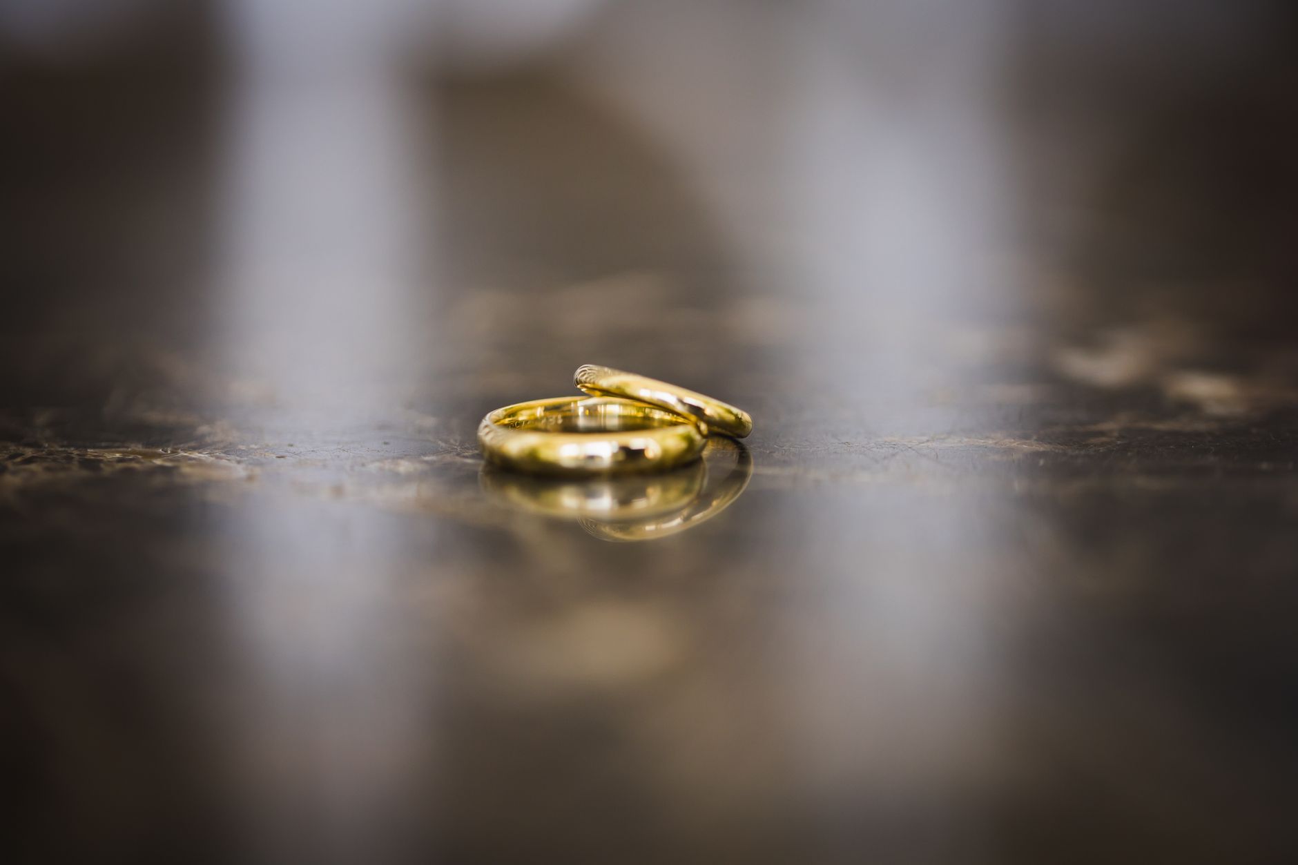 Elegant close-up of golden wedding rings on a reflective marble surface, evoking love and commitment.