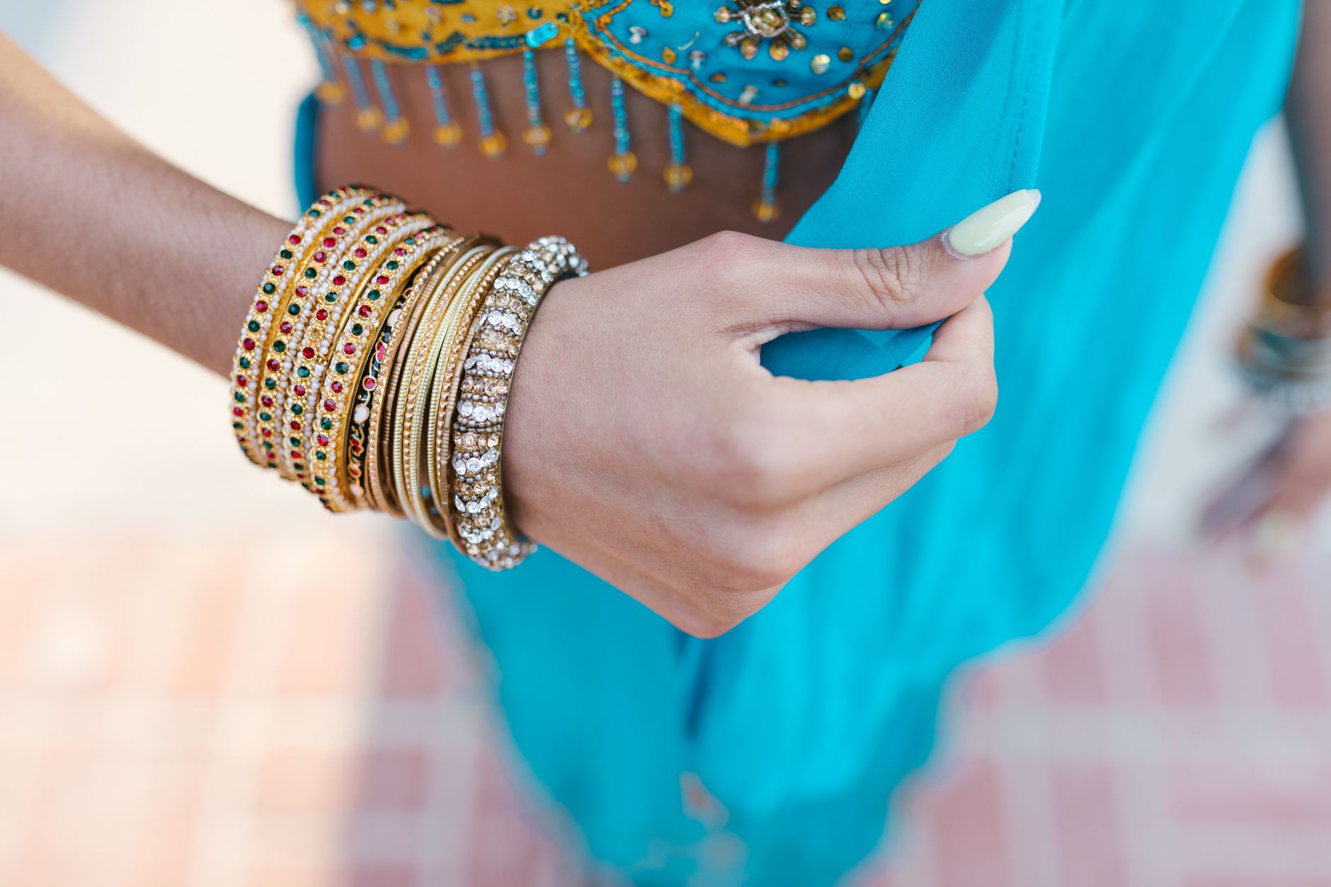 Close-up of colorful bangles on a woman's hand wearing traditional blue attire, showcasing Indian culture.