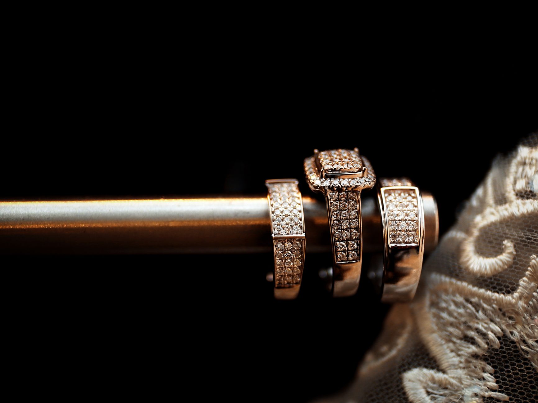 Close-up of luxury diamond wedding rings elegantly arranged with delicate lace in the background.