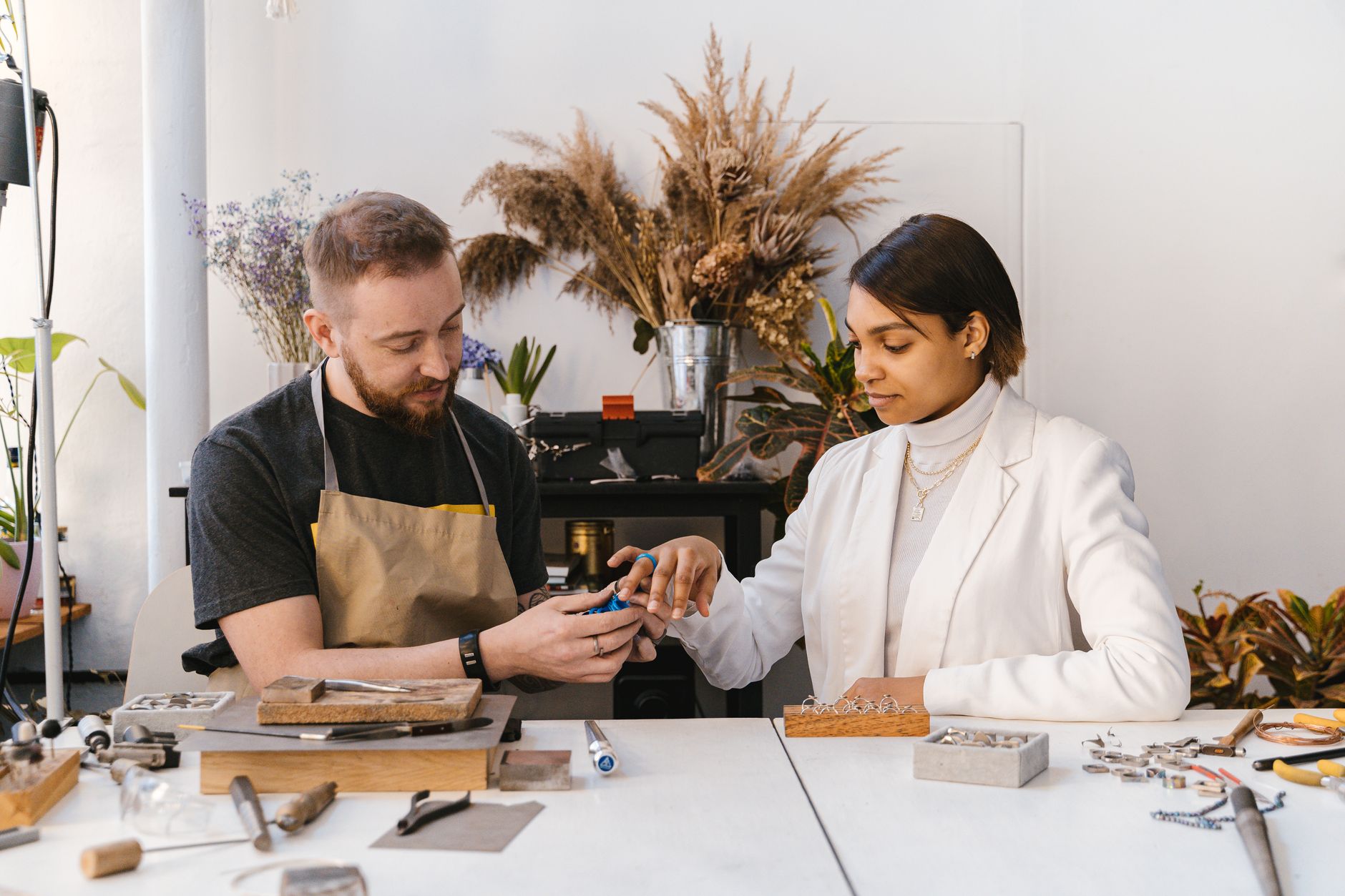 Jewelry craftsman showing a piece to a client in an art studio. Collaborative and creative work environment.