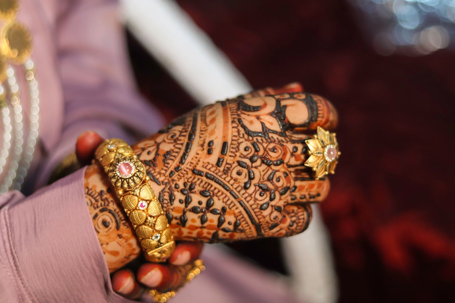 Close-up of a bride's hand adorned with intricate henna and traditional jewelry.