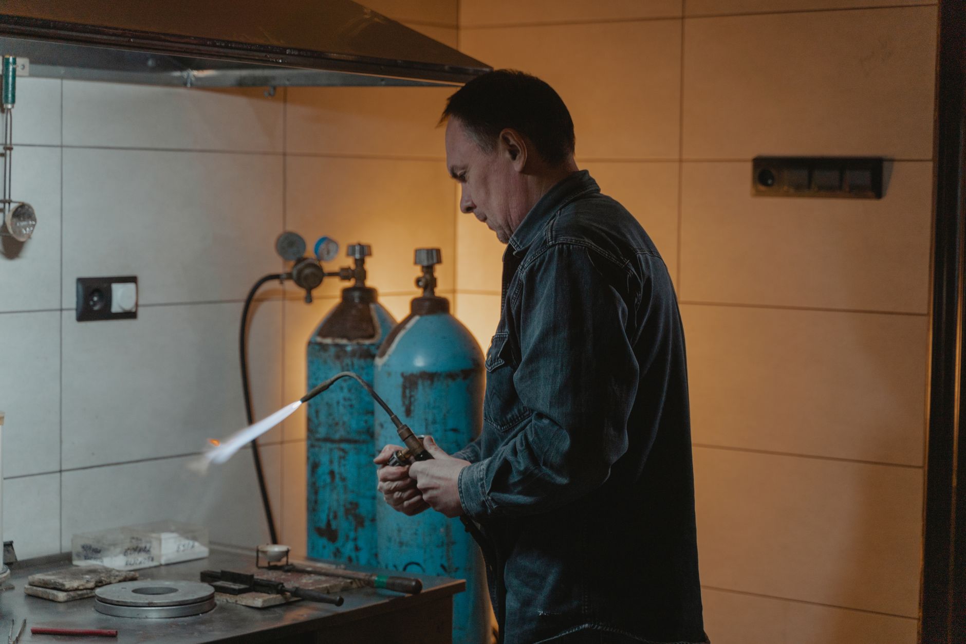 A skilled technician works with a welding torch in an industrial setting, highlighting craftsmanship.