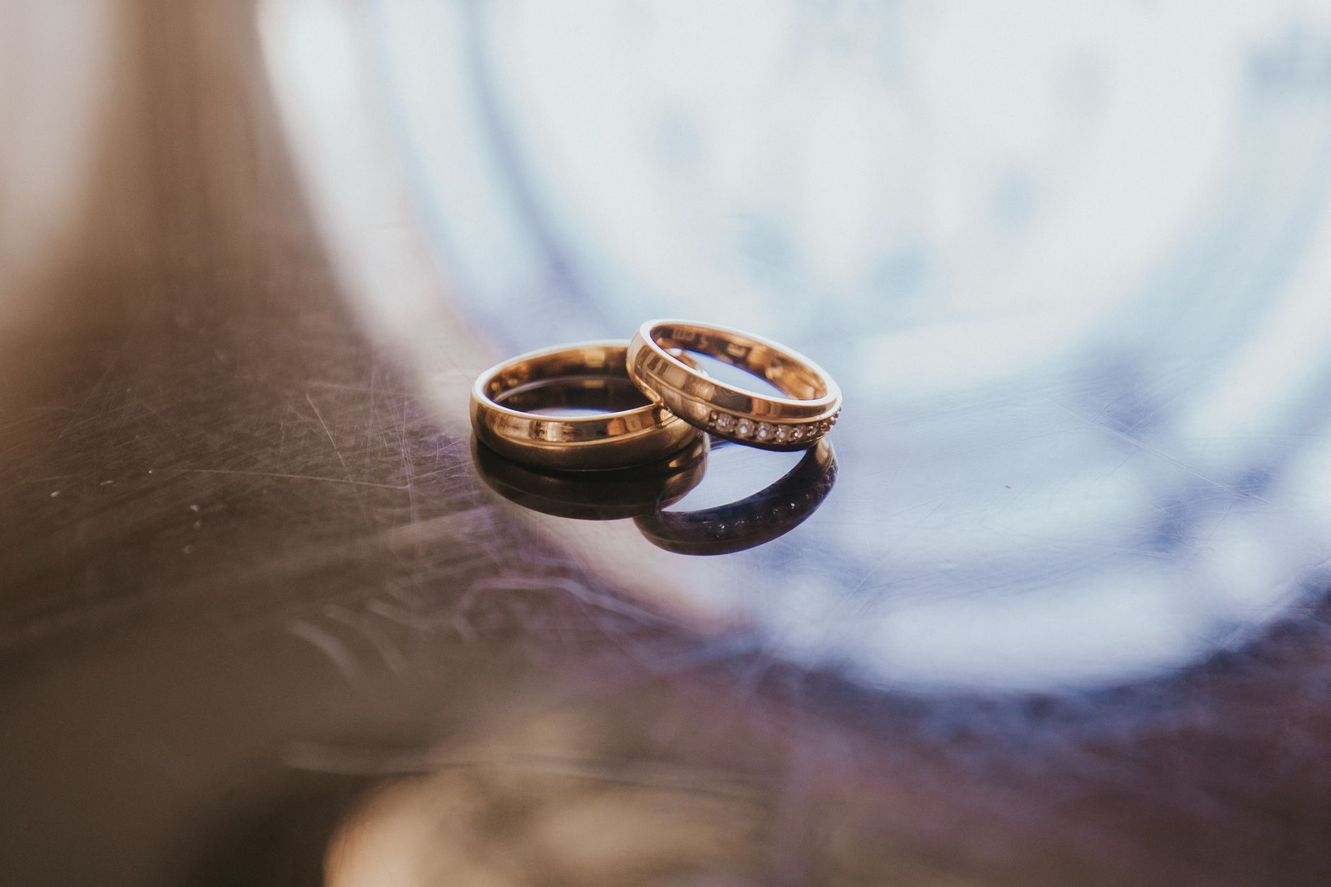 A detailed shot of two elegant gold wedding rings on a reflective surface.