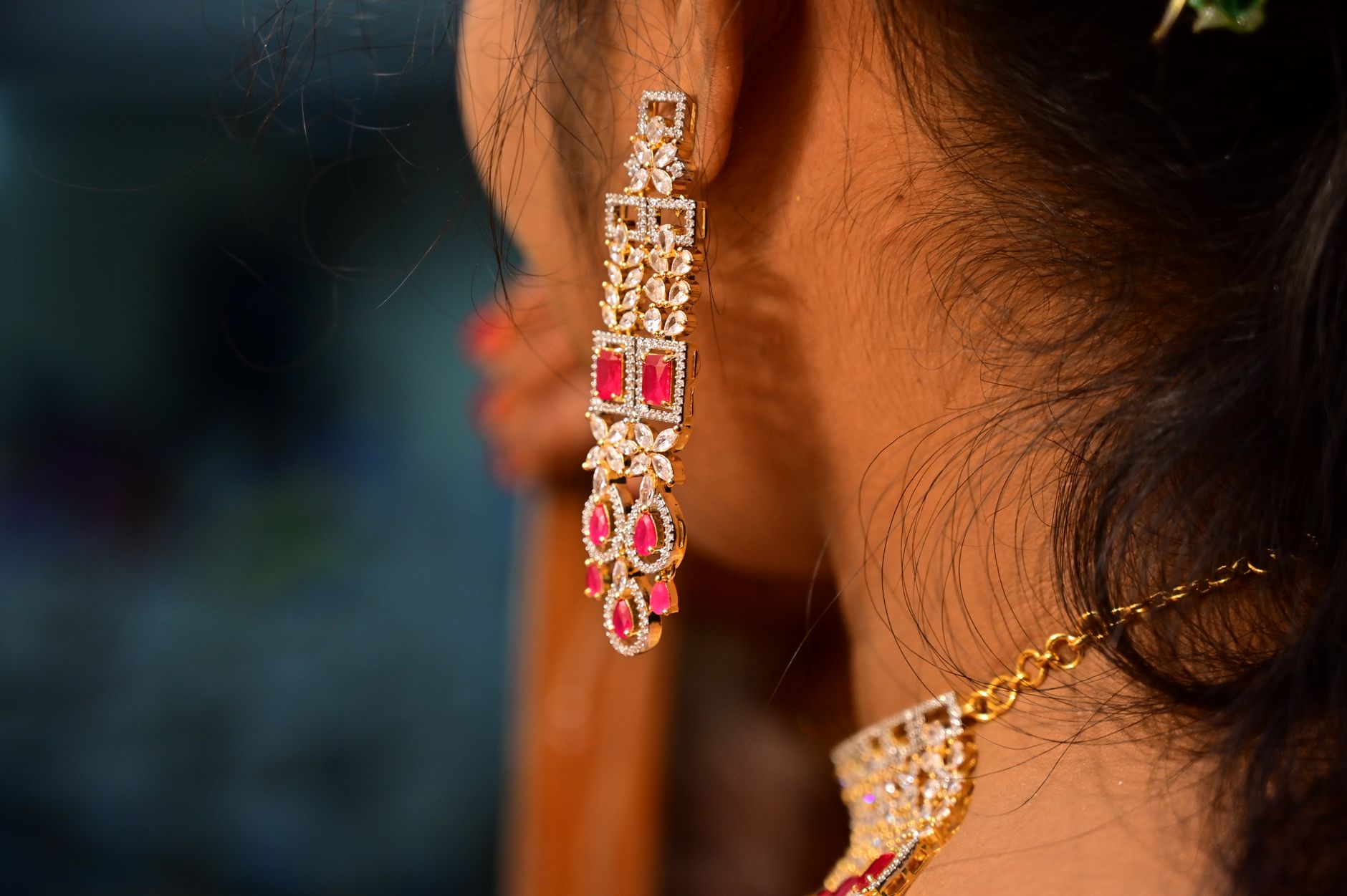 An intricate earring and necklace adorn a woman's ear, showcasing craftsmanship and style.