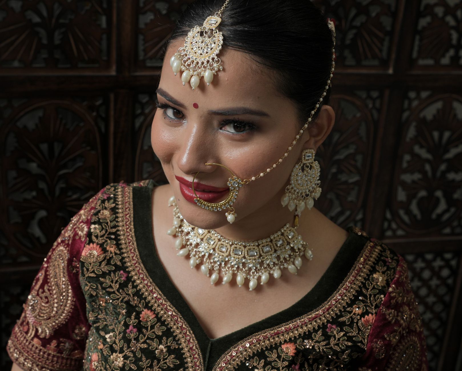A beautiful bride in intricate traditional attire and jewelry with a captivating smile.
