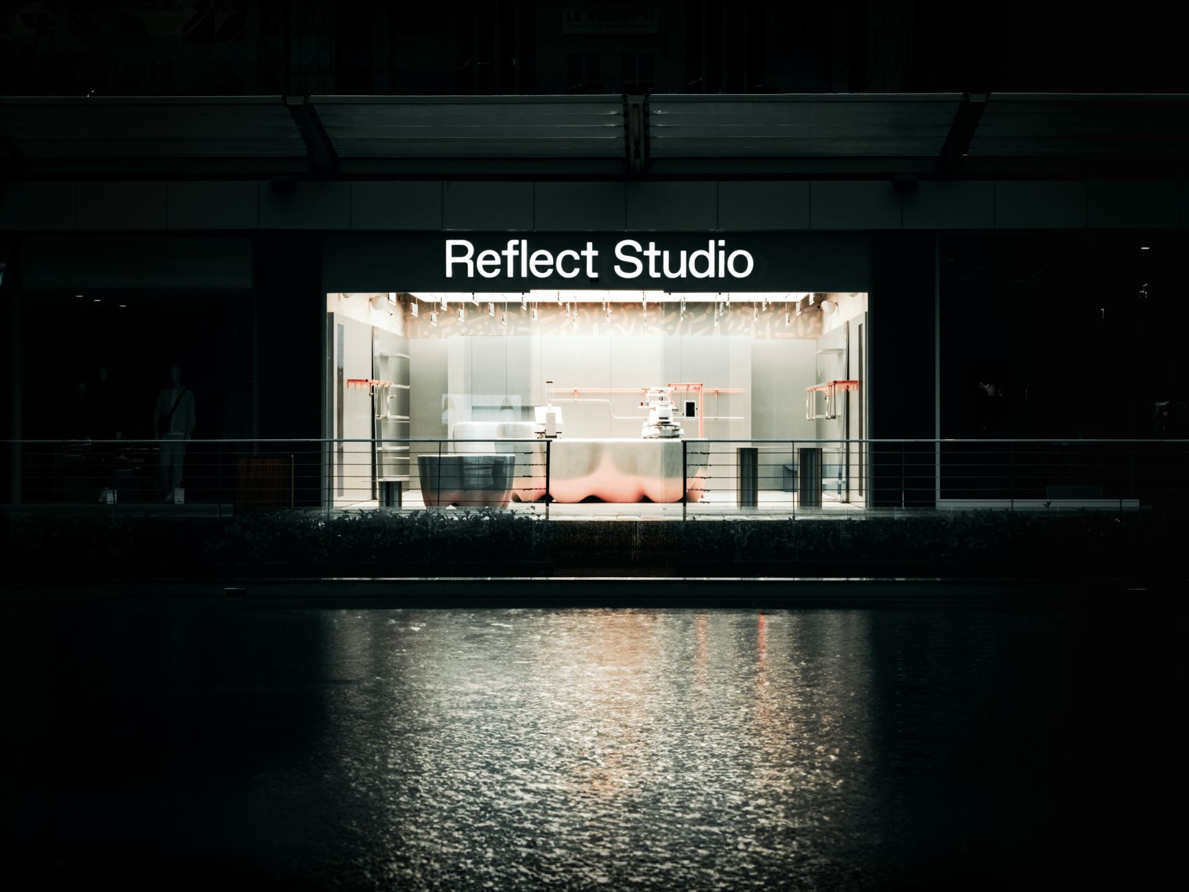 Stylish urban studio exterior in Bursa at night reflecting on water.