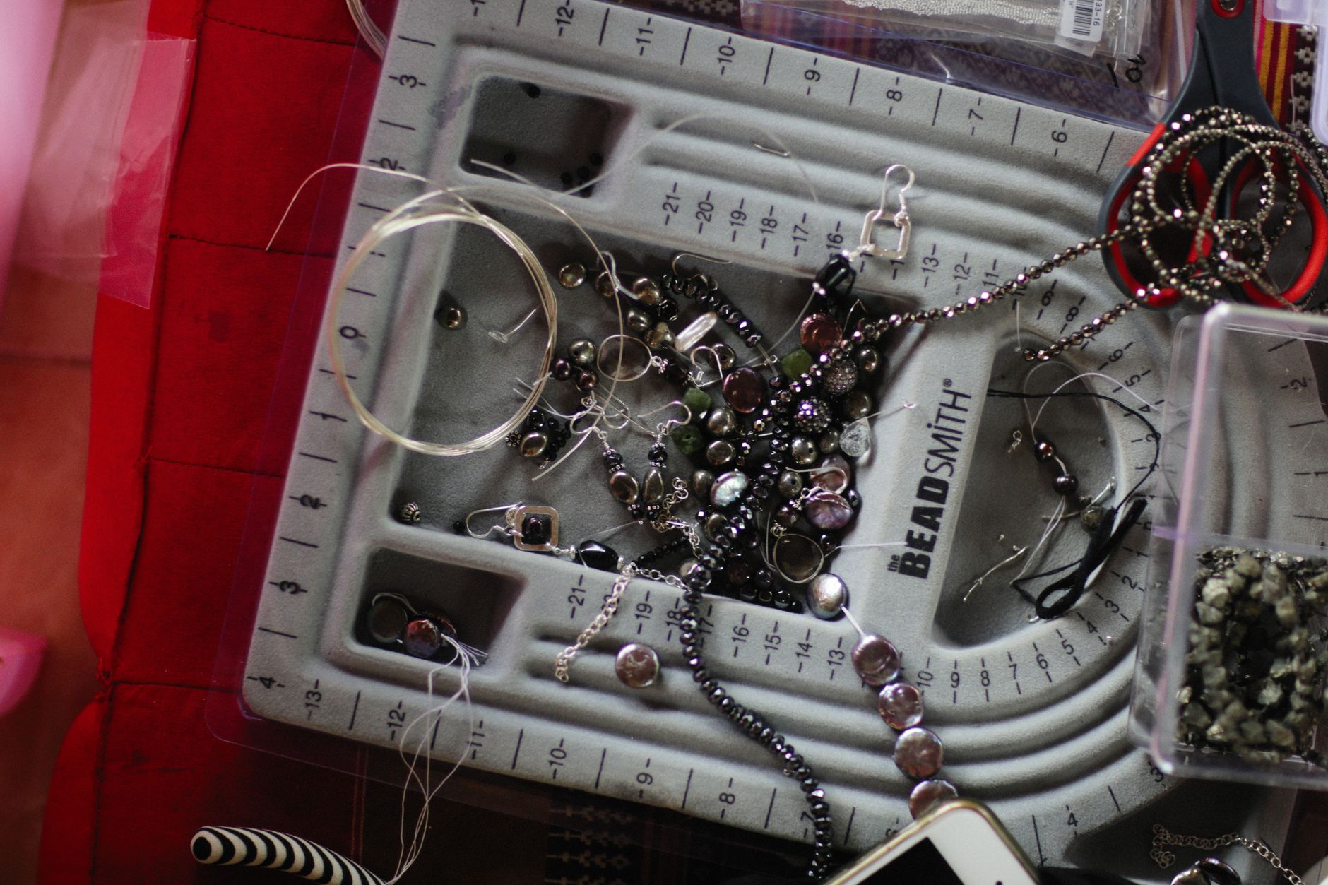 Capture of a jewelry-making workspace with beads, tools, and accessories laid out for crafting.