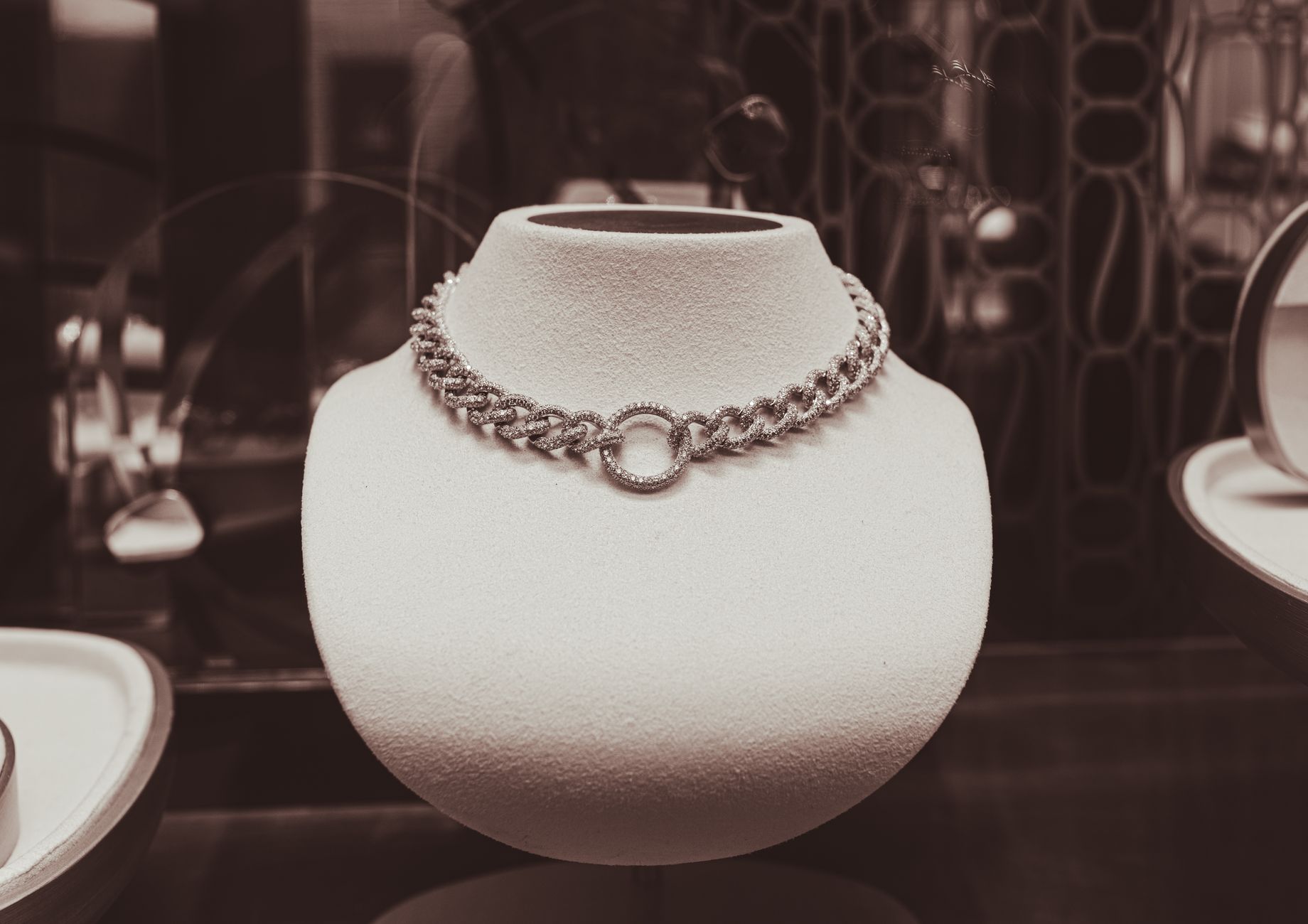 Classic monochrome close-up of a luxury necklace elegantly displayed on a bust in a store setting.