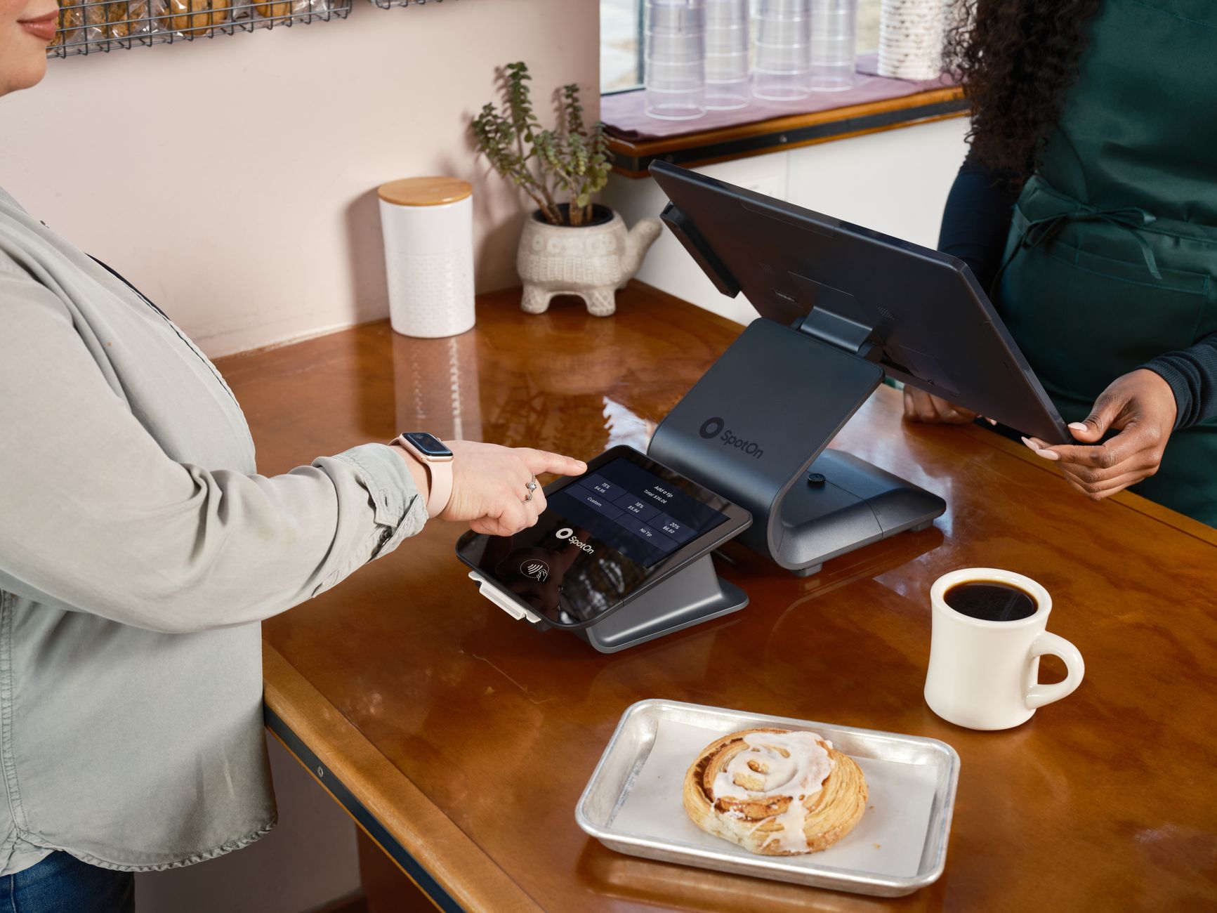 Customer using a digital point of sale system in a cozy café setting, ordering coffee and pastry.