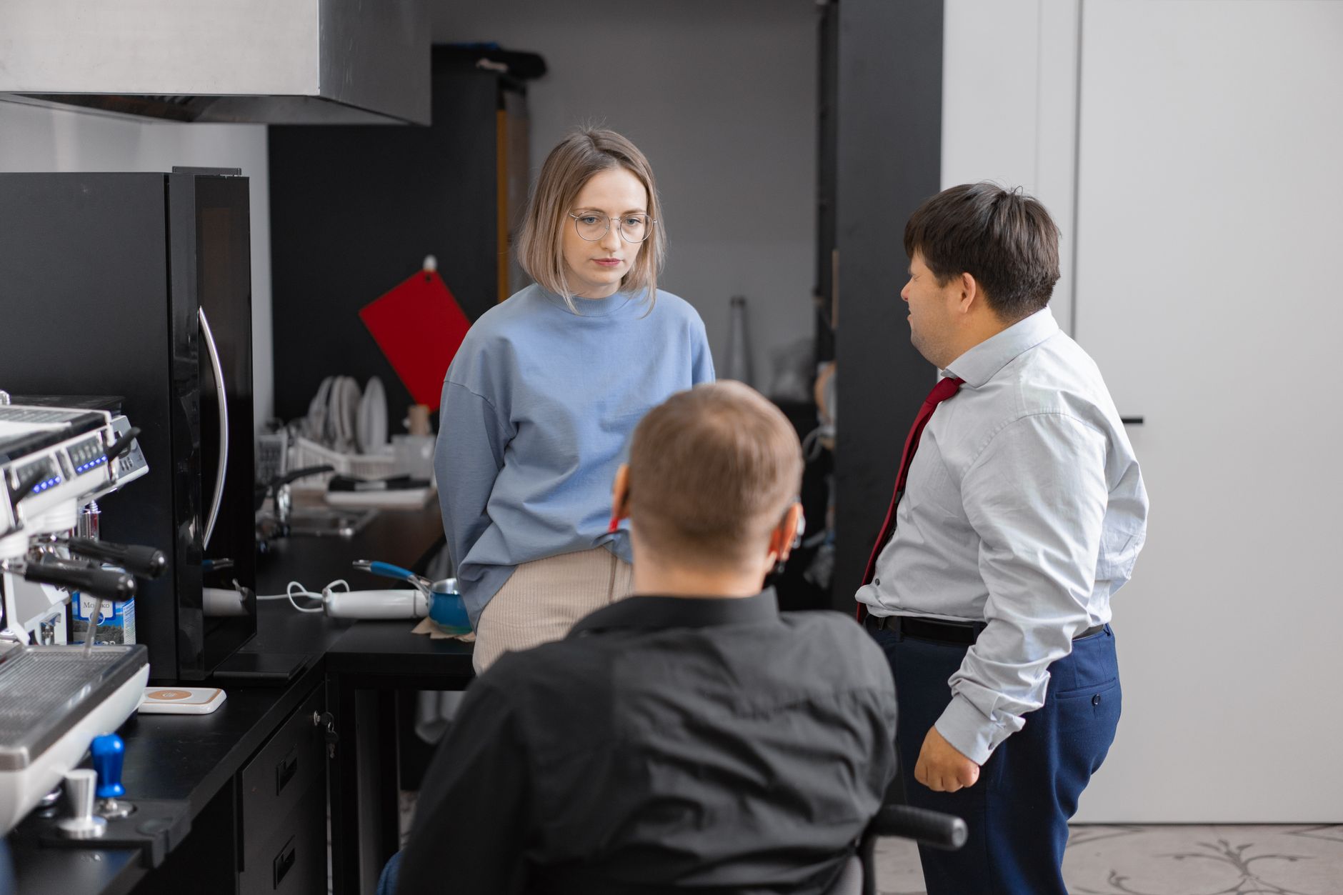 Three colleagues having a discussion in a modern office setting, promoting inclusivity and teamwork.