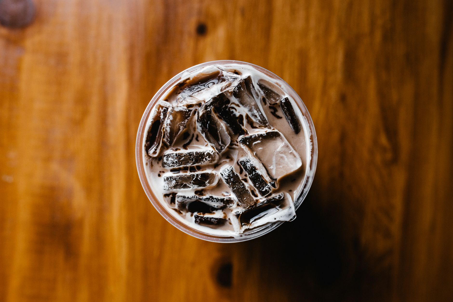 Top view of a refreshing iced coffee with milk on a wooden surface. Perfect for illustrating beverage concepts.