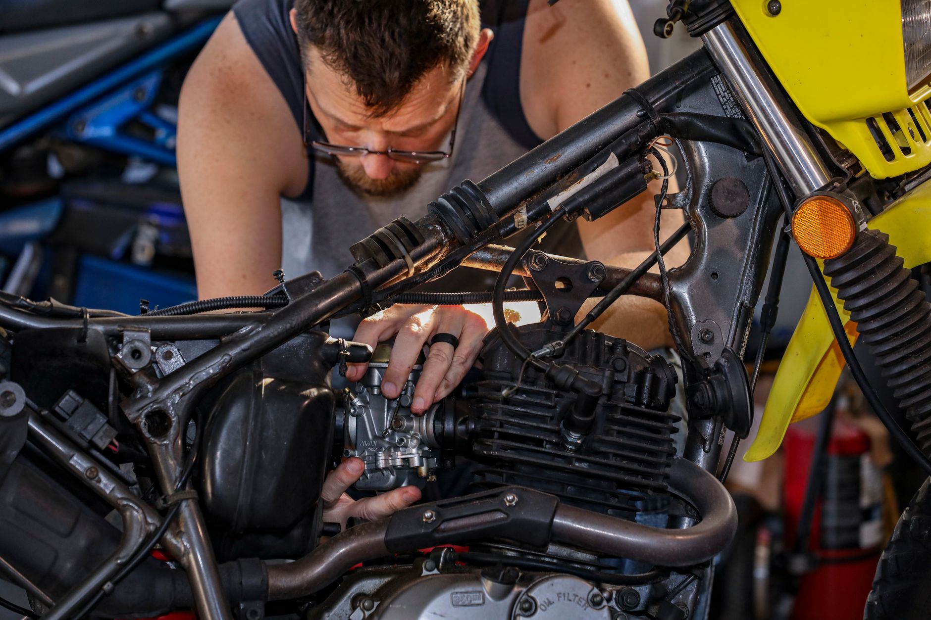 Mechanic focused on repairing a motorcycle engine in garage setting.