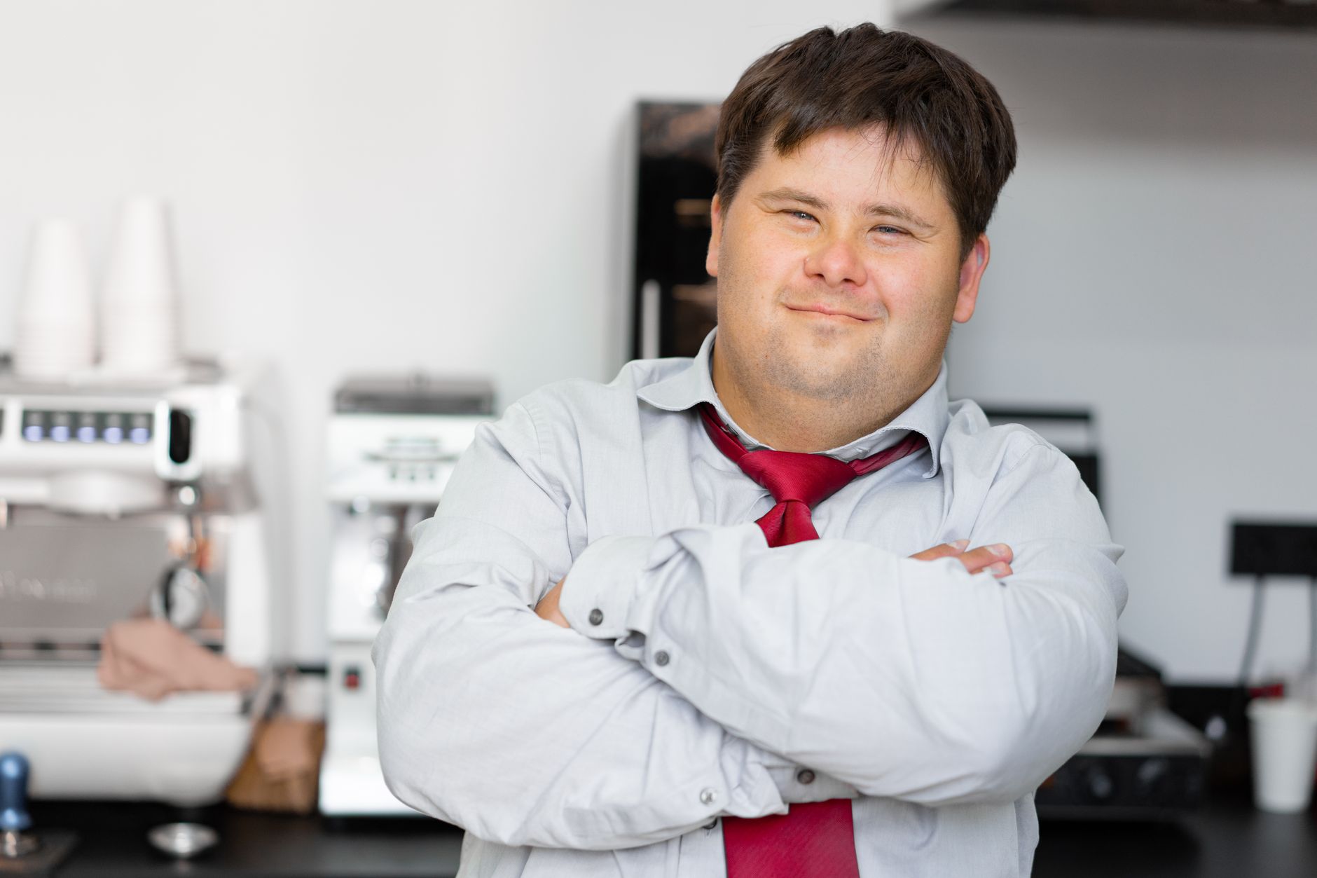 Smiling man with Down syndrome in a work setting, showcasing confidence and inclusivity.
