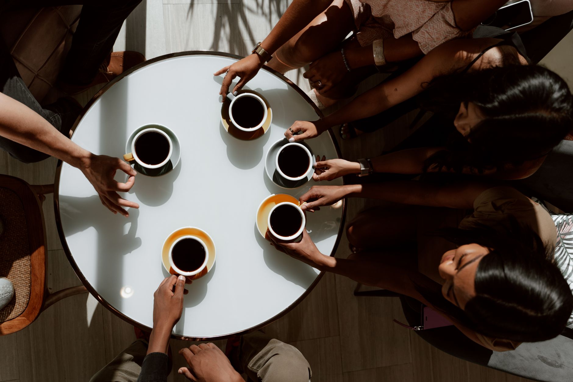 Group of friends gathered around a table, sharing coffee in a cozy setting.