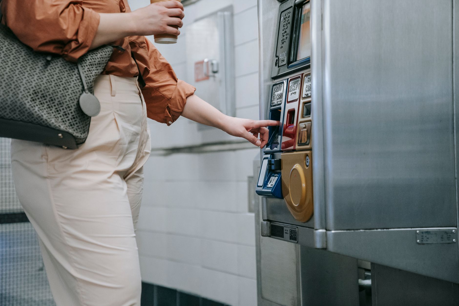 A woman uses a ticket machine in an indoor urban transit setting.