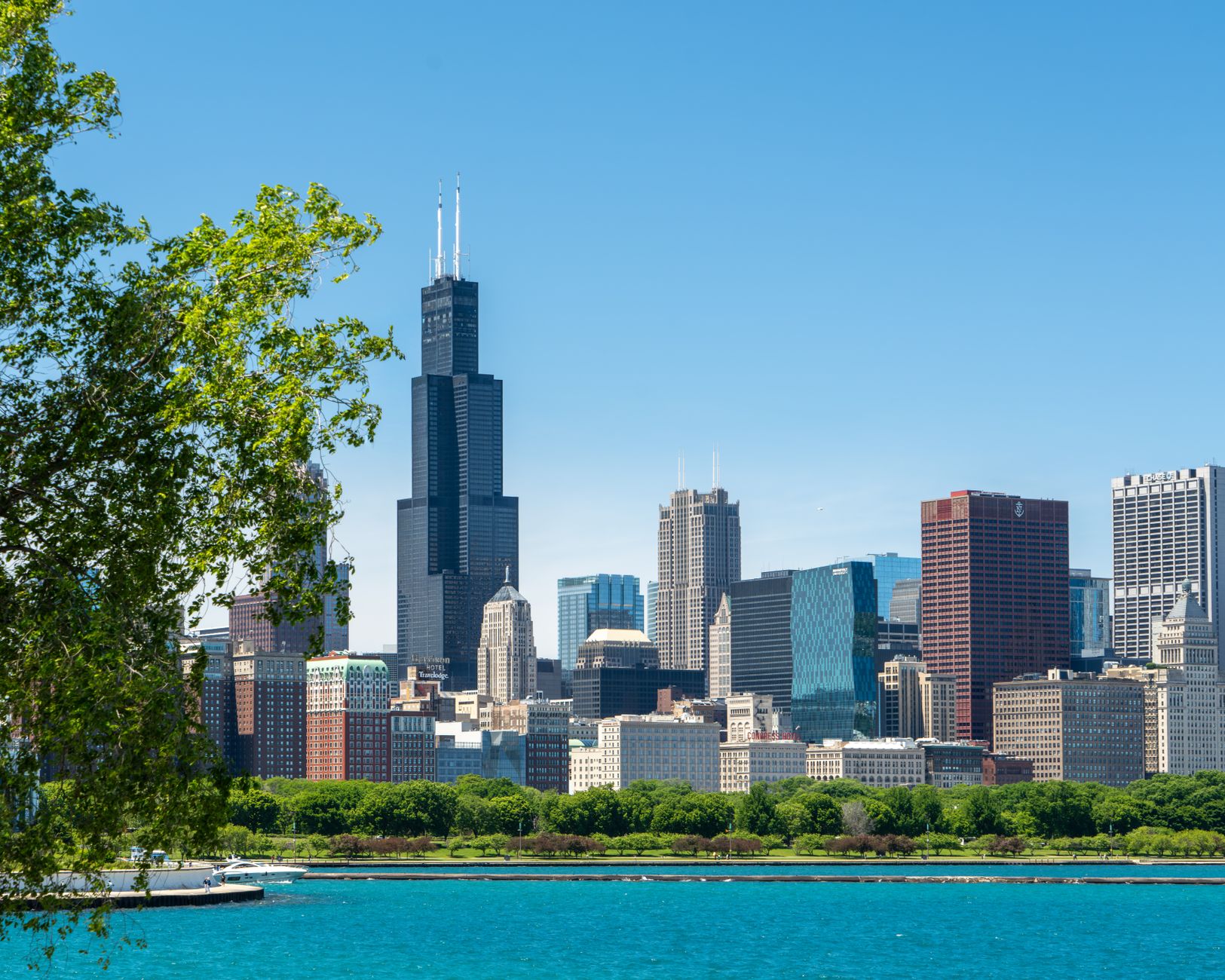A vibrant view of Chicago skyline featuring the iconic Willis Tower under clear summer skies.