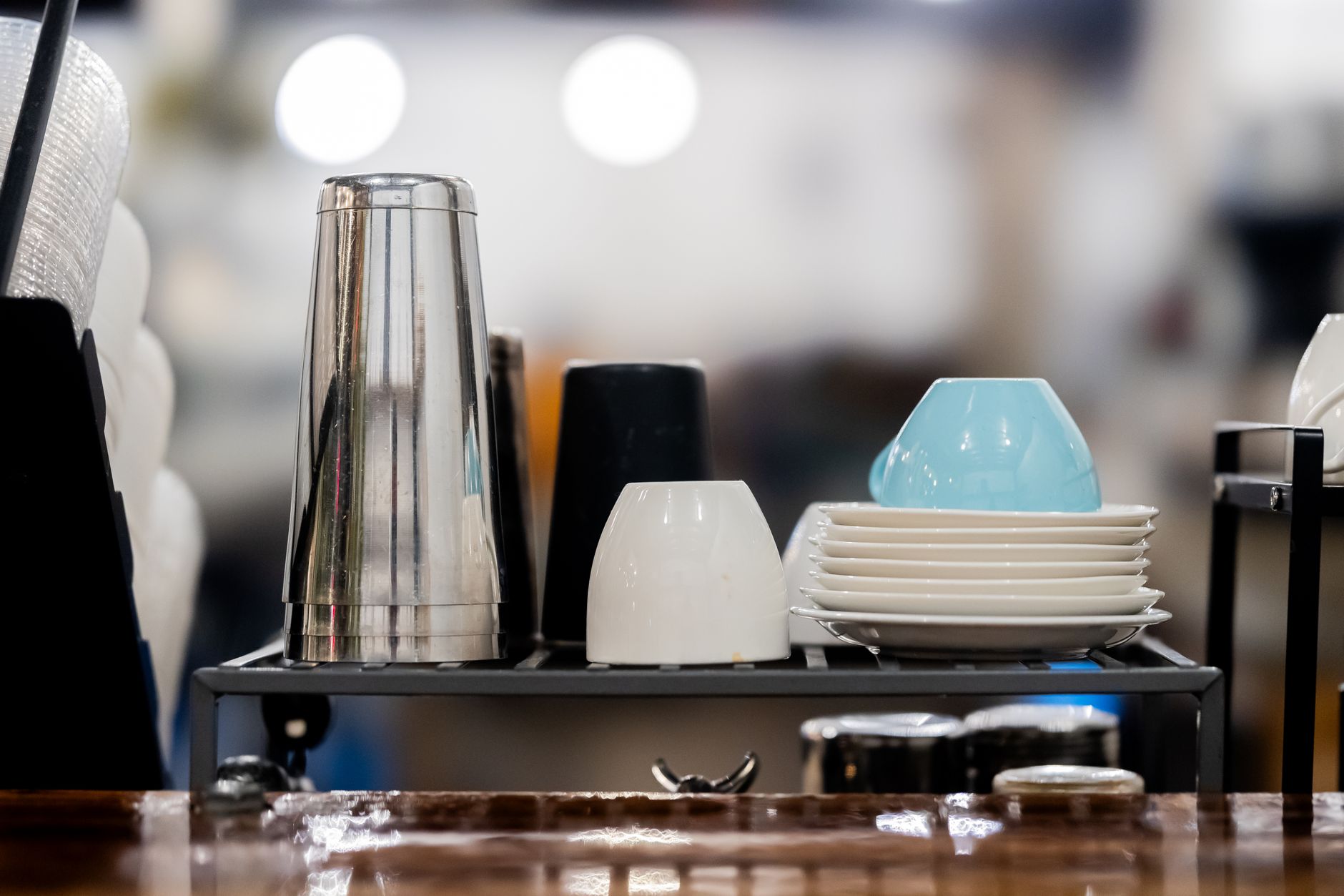 Stacked cups and plates on a cafe countertop creating a cozy setting.