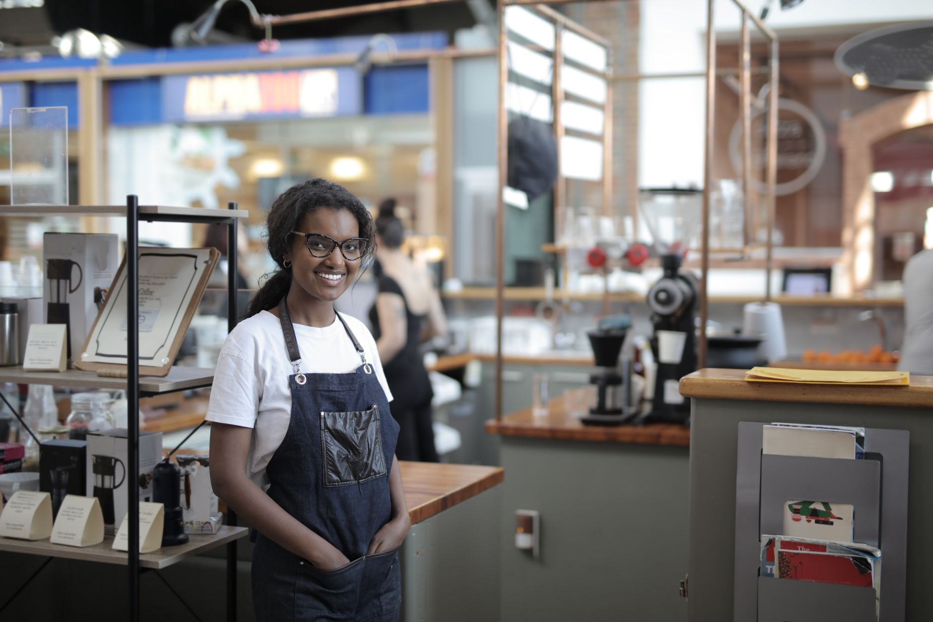 Smiling barista standing in a stylish café, showcasing entrepreneurial spirit.