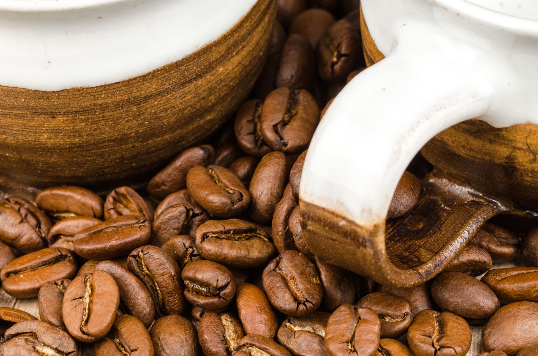 Aromatic coffee beans and rustic ceramic mugs in a close-up shot, highlighting texture and caffeine appeal.