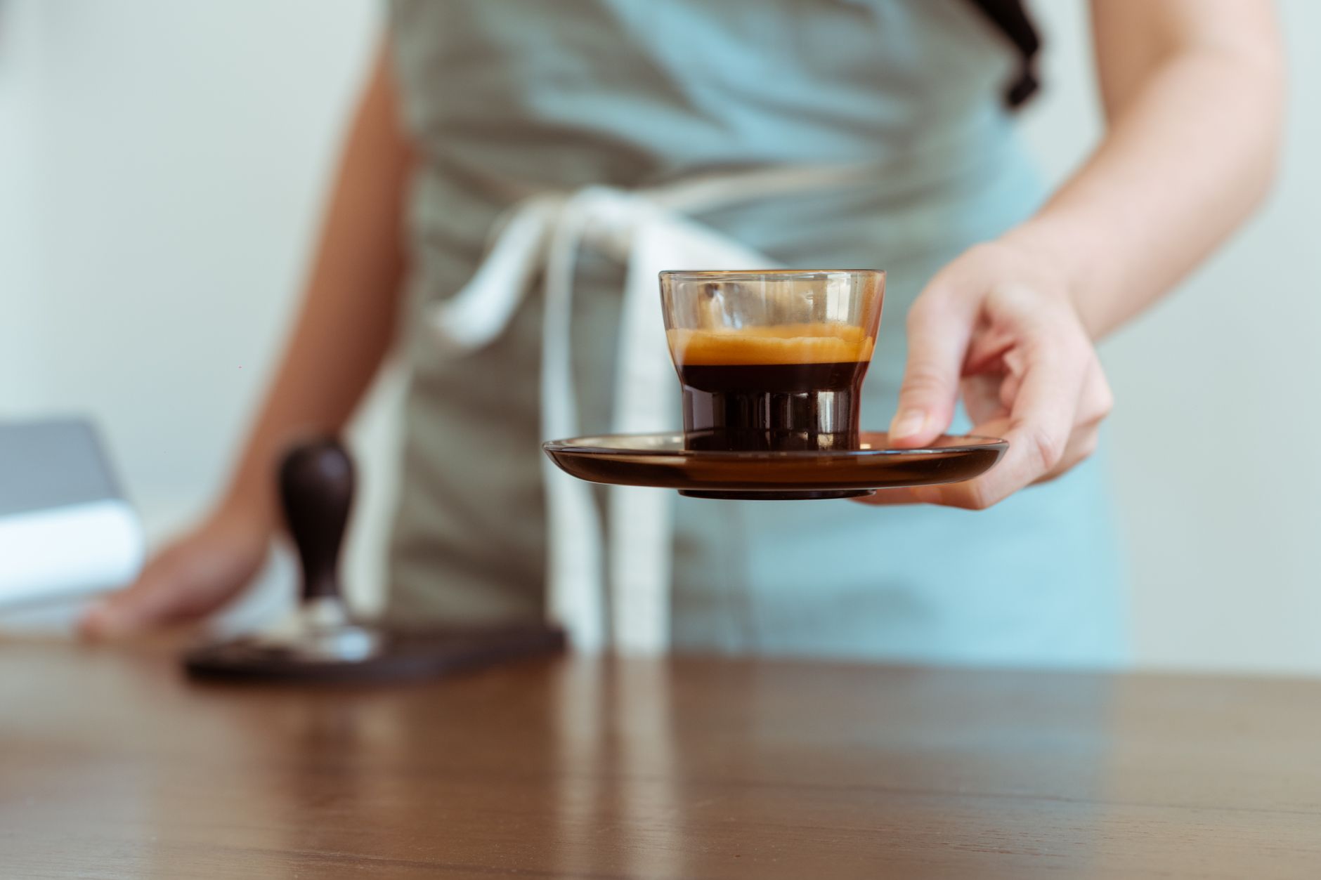 Crop unrecognizable cafe worker with small cup of fresh strong black coffee just brewed for client