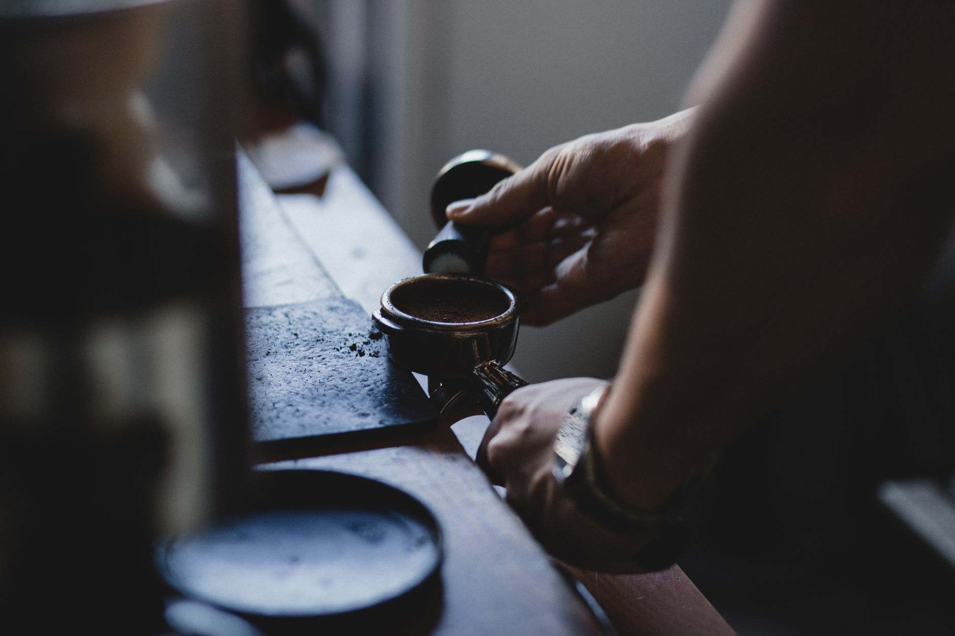 Close-up of a barista's hands preparing espresso indoors, creating a cozy coffee atmosphere.