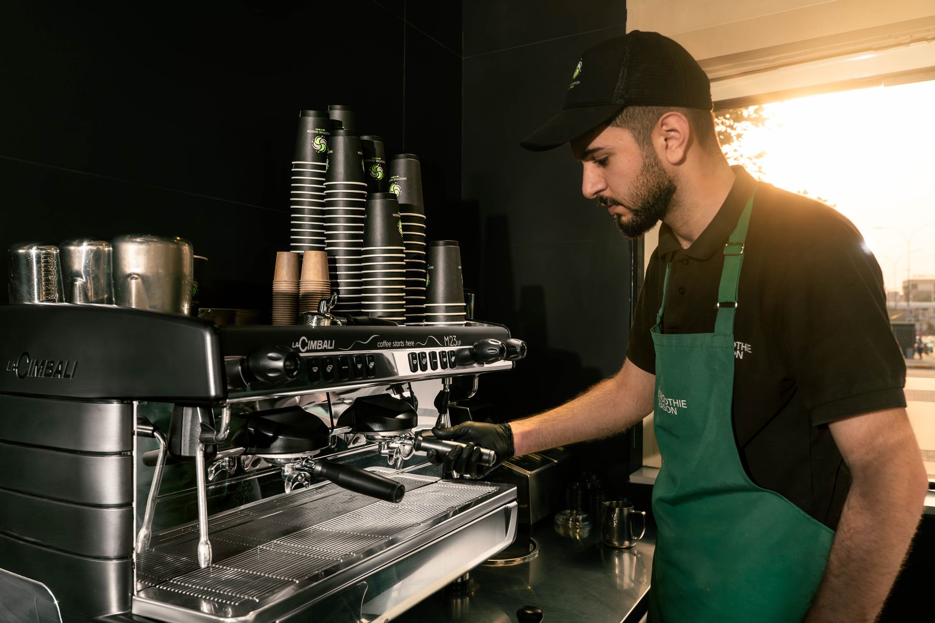 Skilled barista using espresso machine in an Erbil cafe, demonstrating coffee-making expertise.