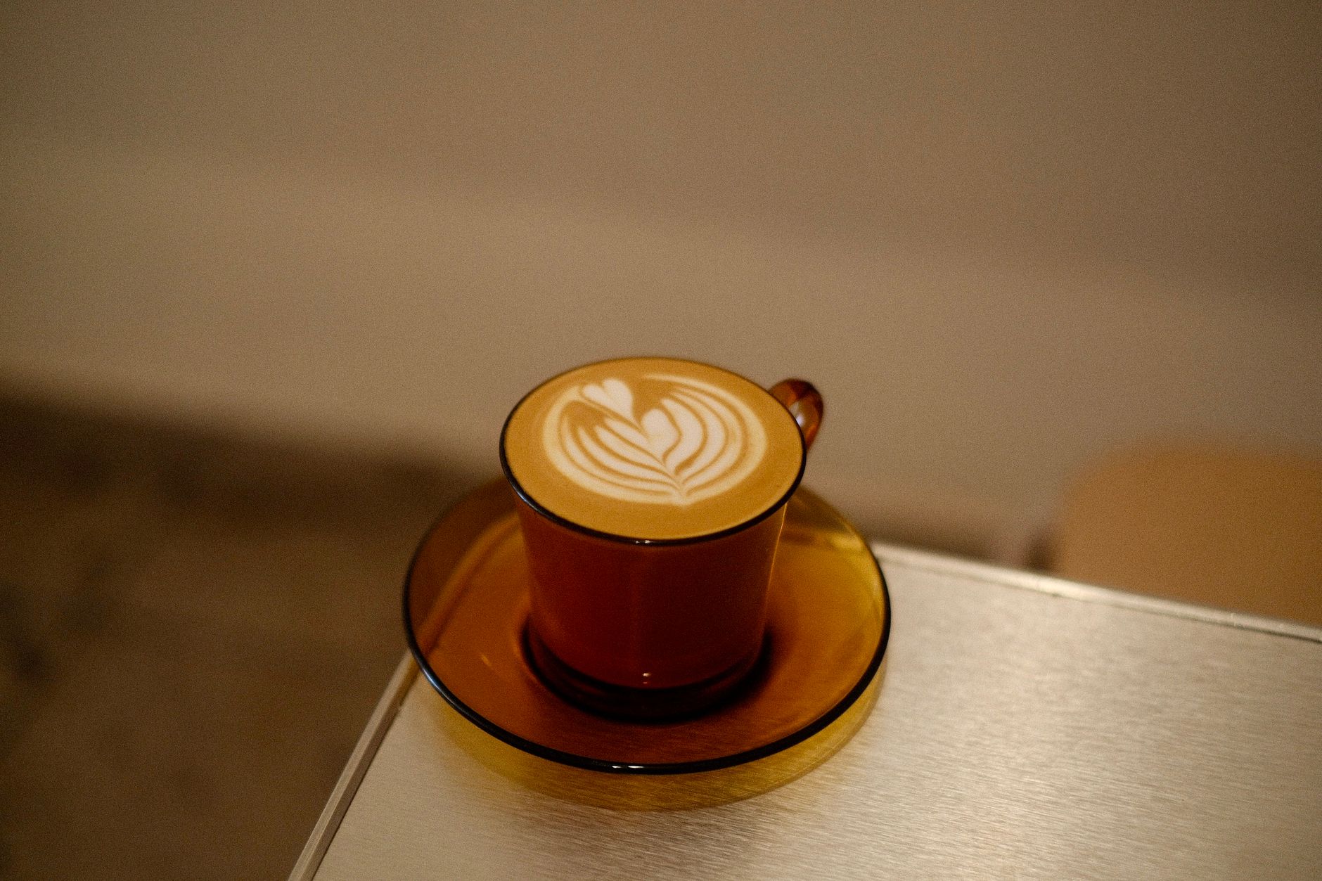 A beautifully crafted latte with intricate art in a warm-toned vintage setting, evoking a sense of coziness.