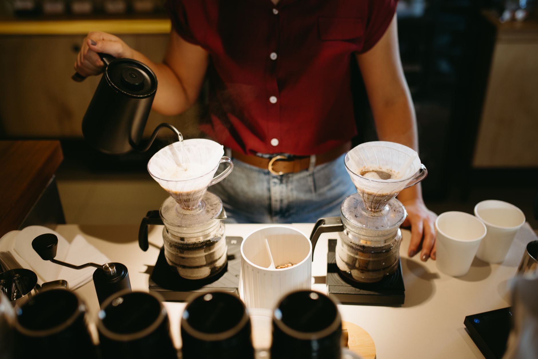 Barista preparing coffee using pour-over method in a café setting, capturing the artisanal brewing process.