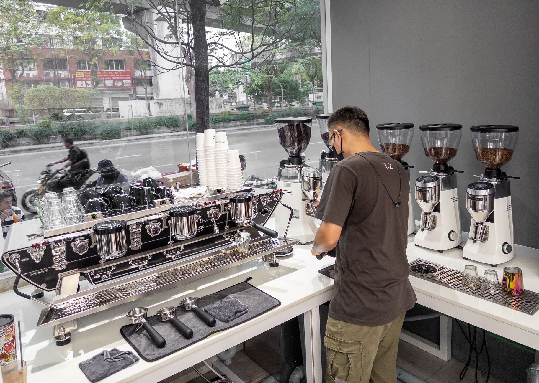 Barista crafting espresso with commercial machines in trendy urban café interior.
