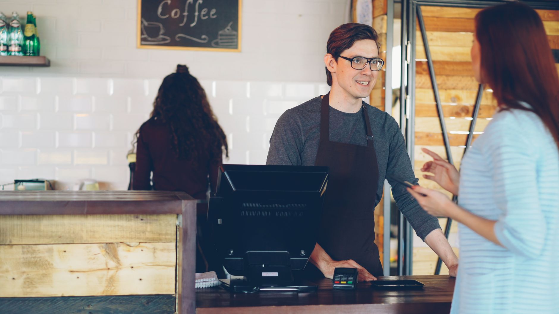 Warm interaction between barista and customer in a cozy coffee shop.