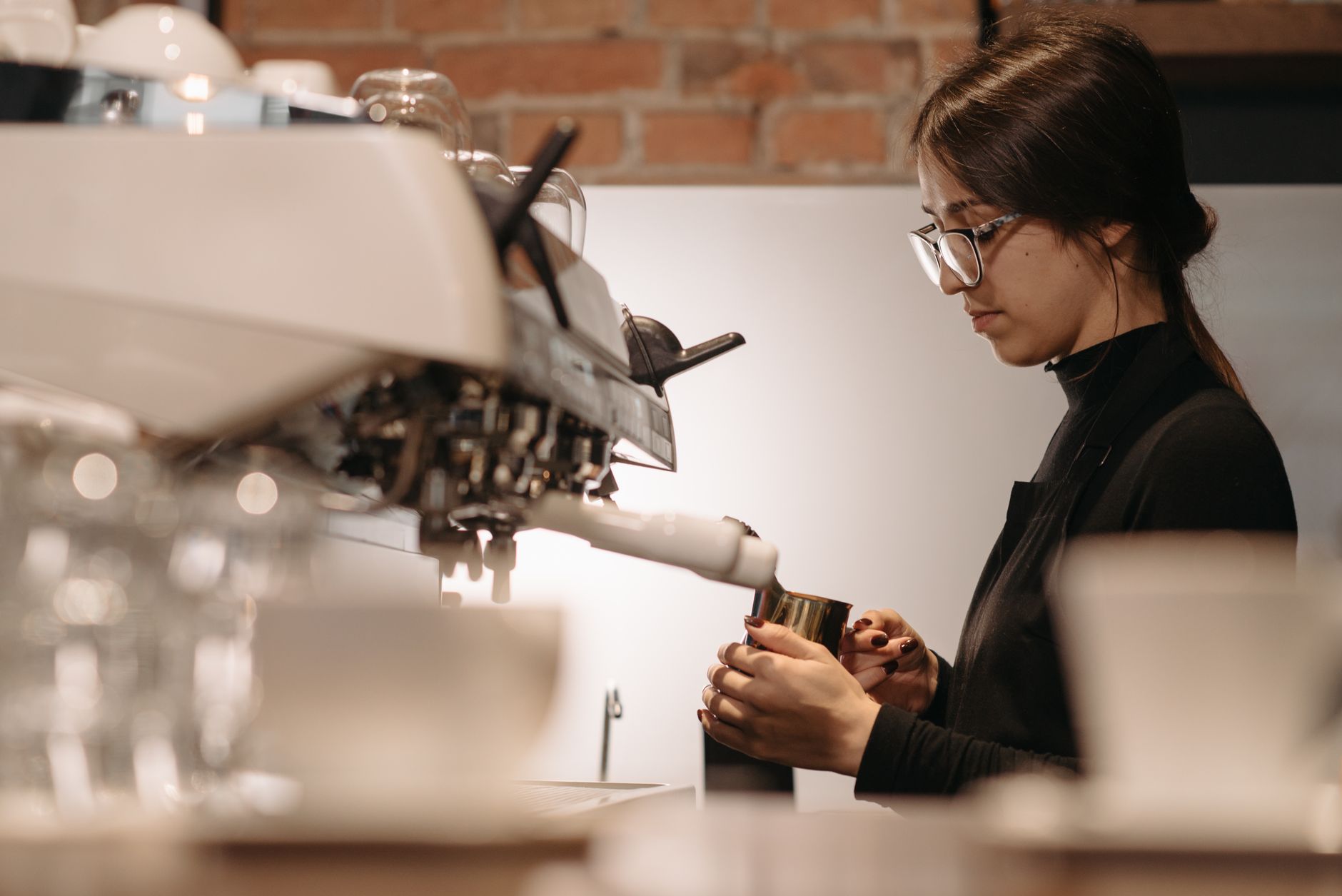 A focused barista expertly brews coffee using an espresso machine in a cozy cafe setting.