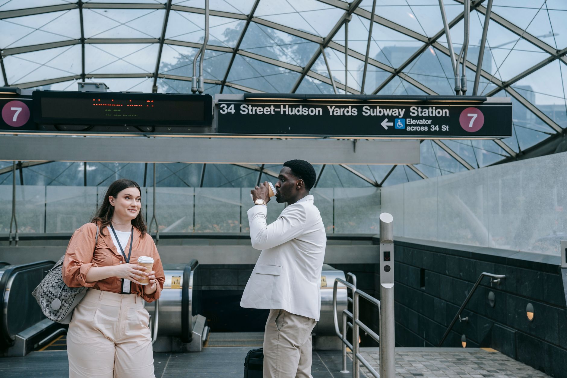 Two adults interacting at 34 Street-Hudson Yards Subway Station in an urban setting.