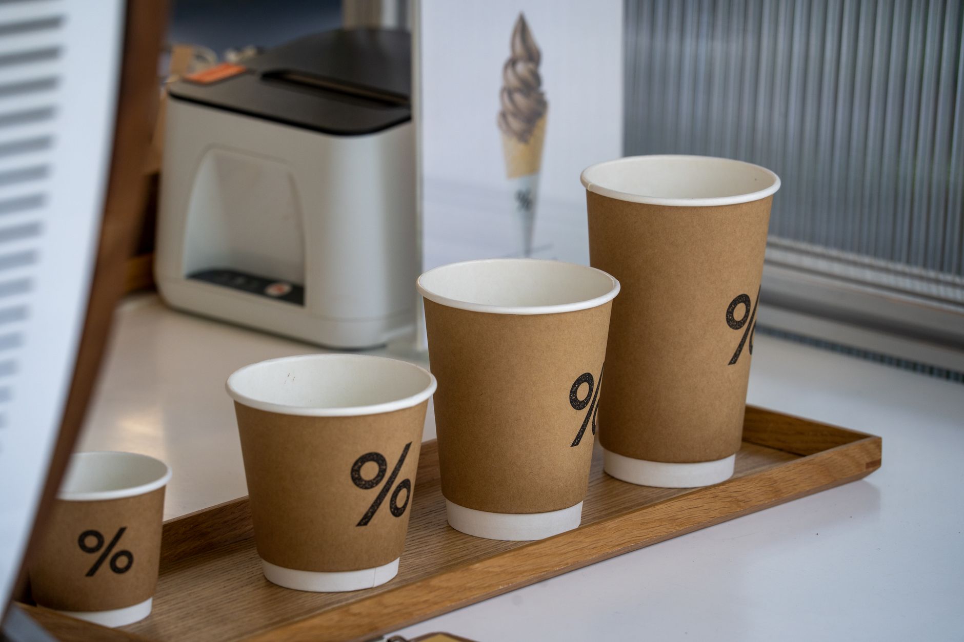 A set of eco-friendly paper cups with percentage signs displayed in a coffee shop setting.