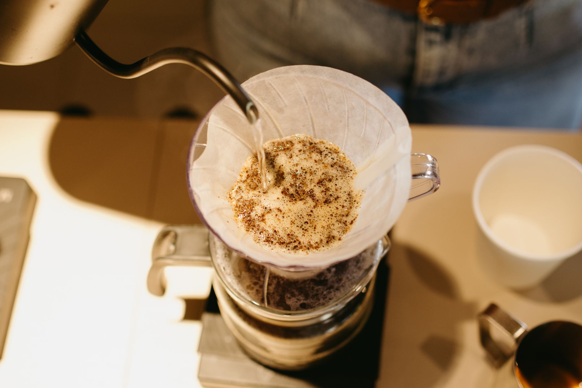 Close-up of a barista preparing pour over coffee with precision.