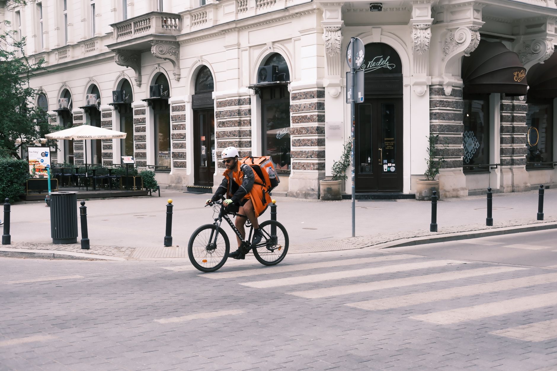 Cyclist with delivery backpack riding through Warsaw's streets, Poland.