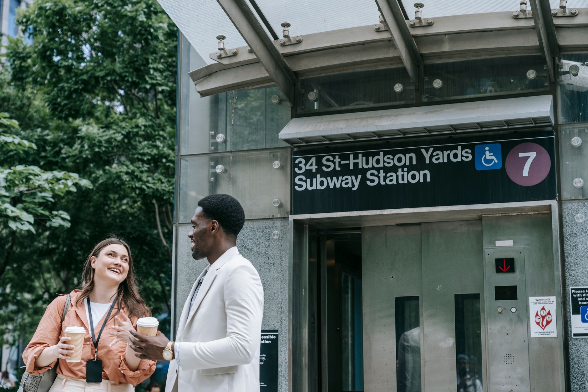 Two colleagues enjoy a coffee break outside 34 St-Hudson Yards Subway Station in NYC.