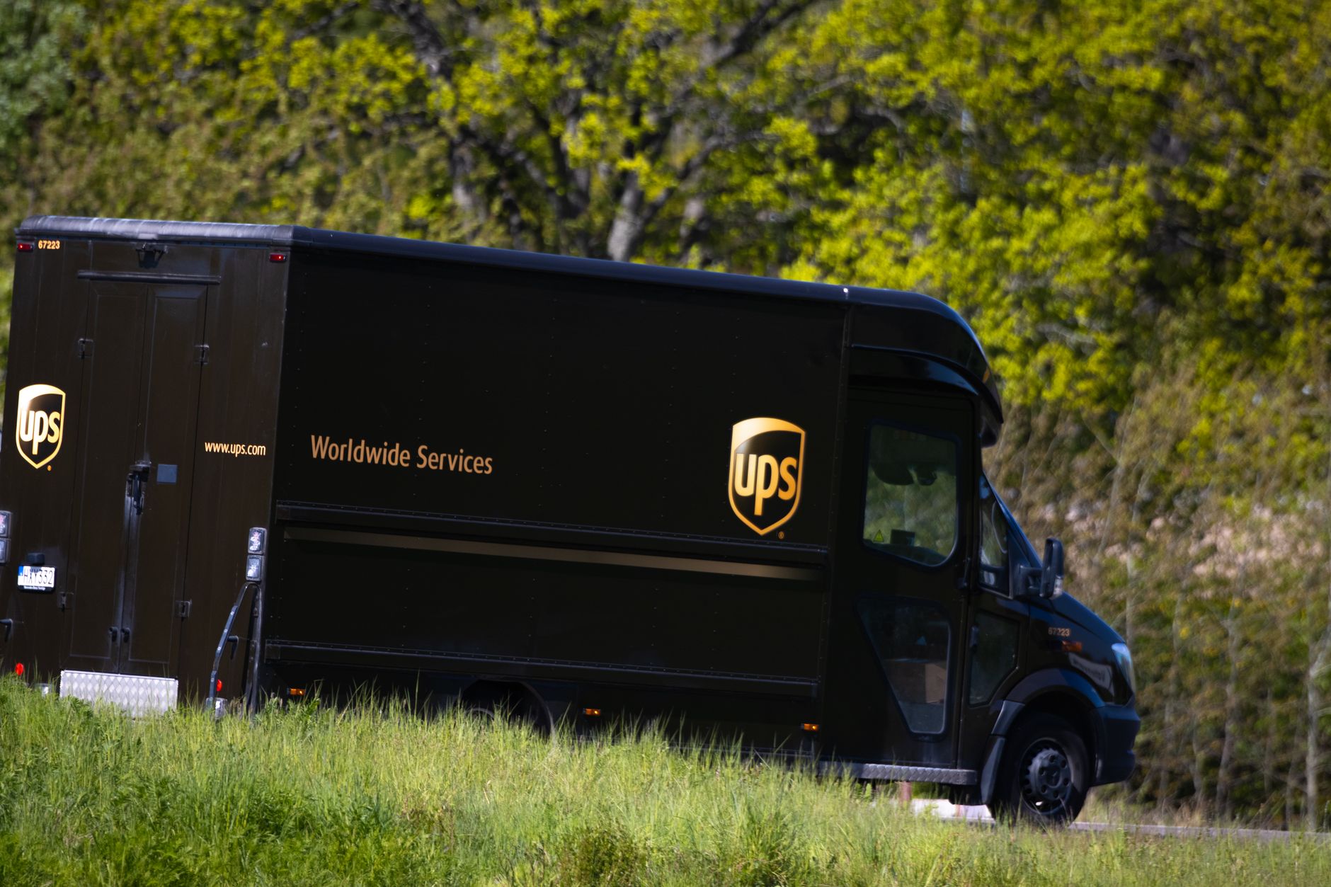 UPS delivery truck driving on a road in Jönköping, Sweden, surrounded by lush greenery.