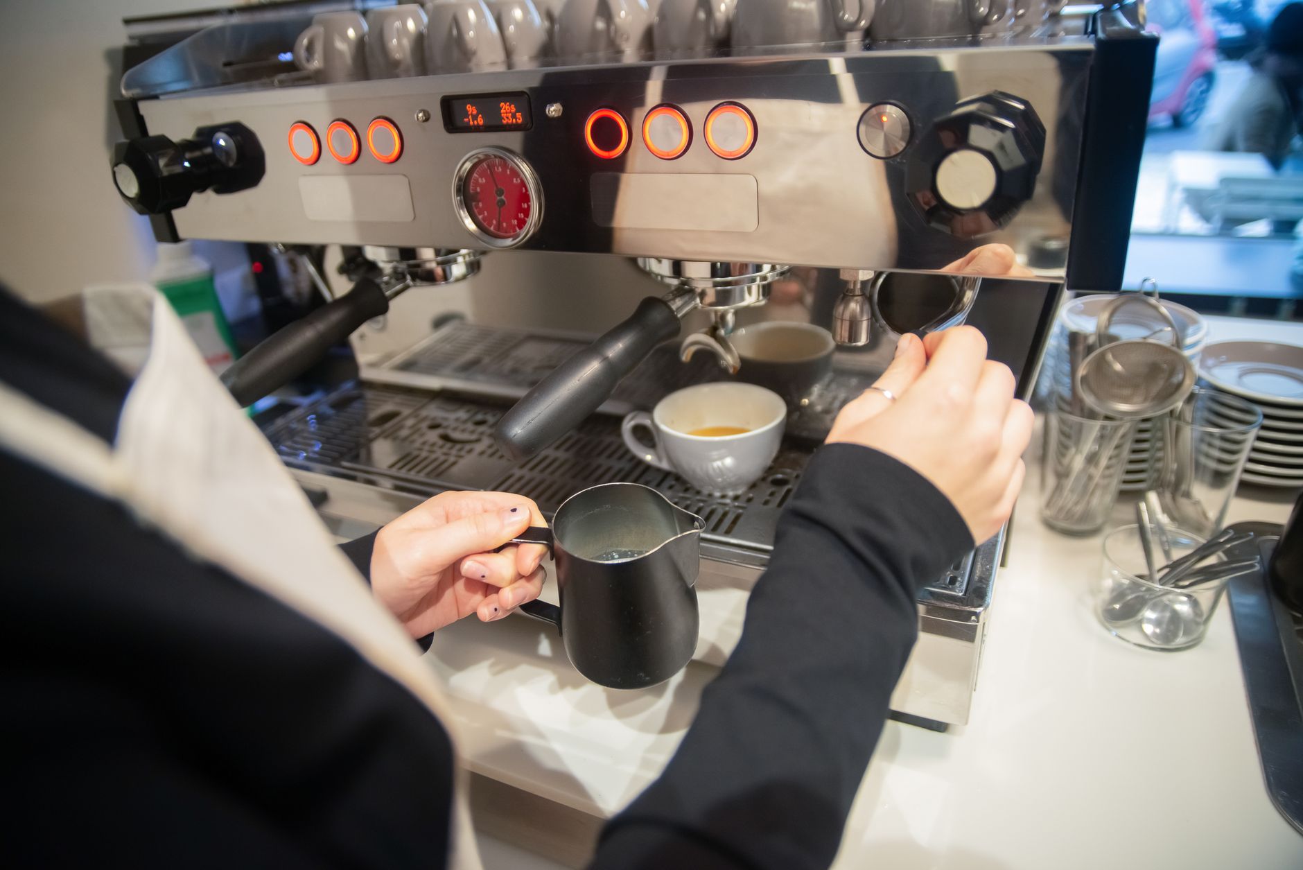 A barista prepares an espresso drink using a modern coffee machine in a café setting.