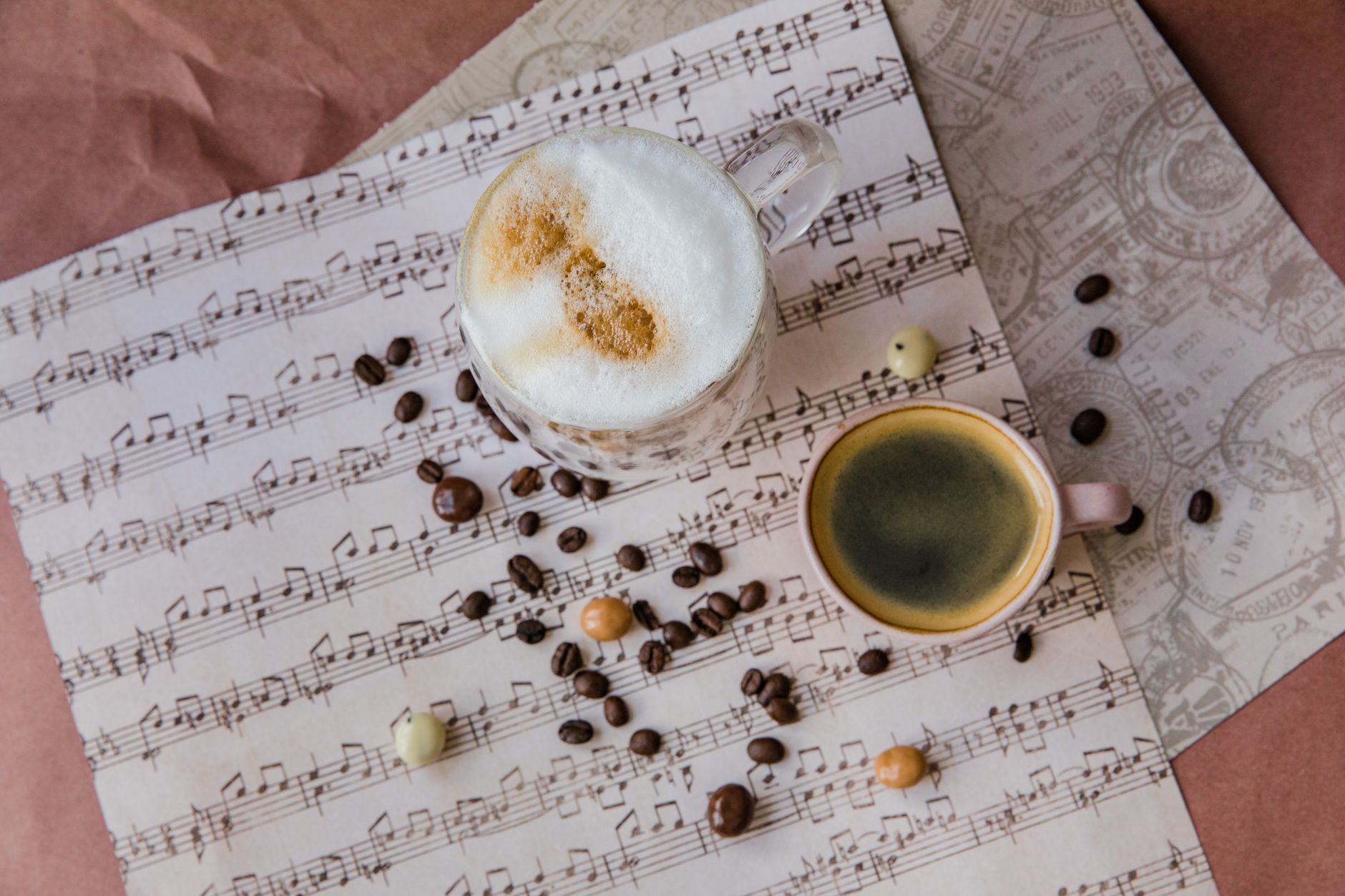 Creative flat lay of coffee cups and beans on music sheet for a cozy ambiance.
