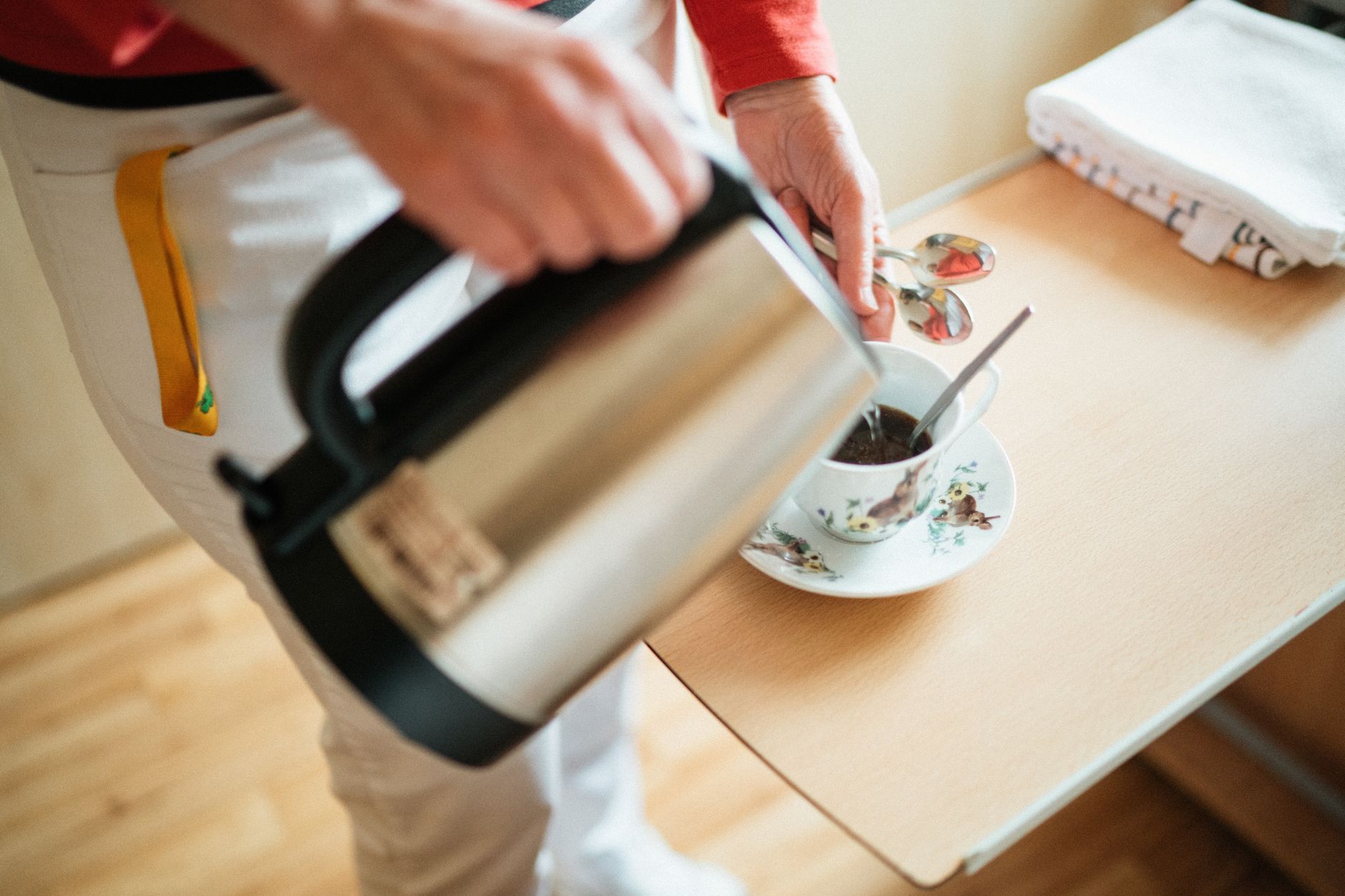 A caregiver pouring coffee into a cup in a cozy setting, highlighting daily life in a retirement home.