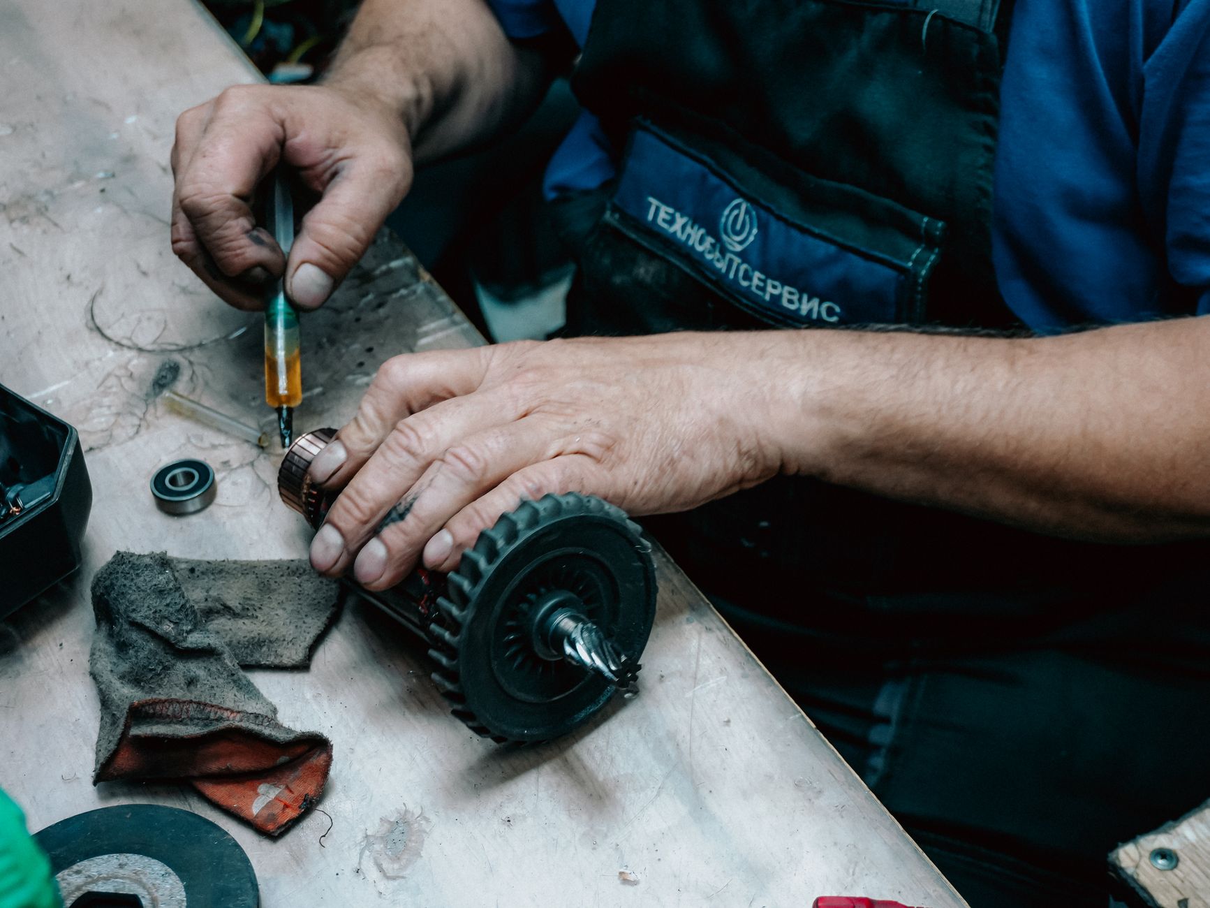 Detailed view of a technician working on a mechanical gear part with precision tools on a workbench.