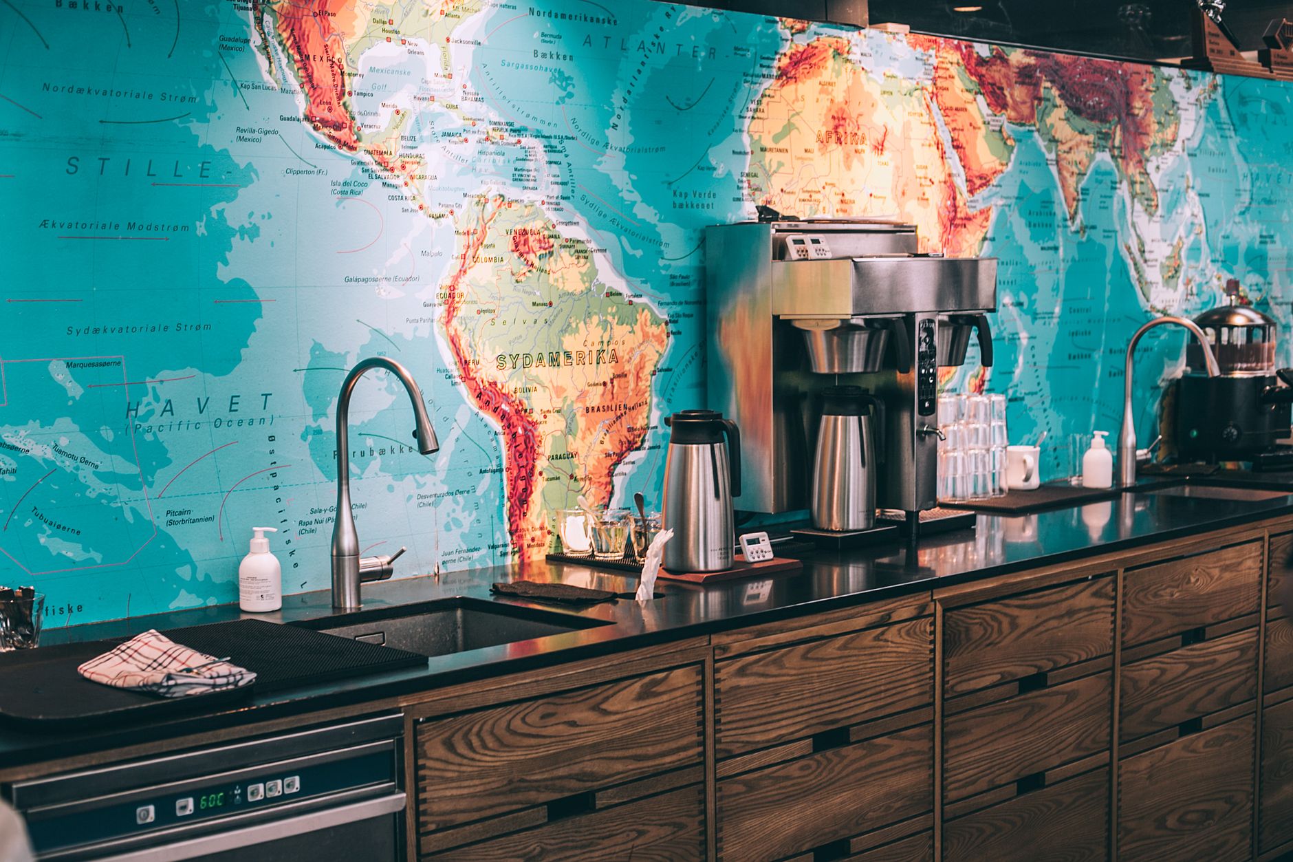 Interior of modern kitchen with coffeemaker in cafeteria with world map as decoration