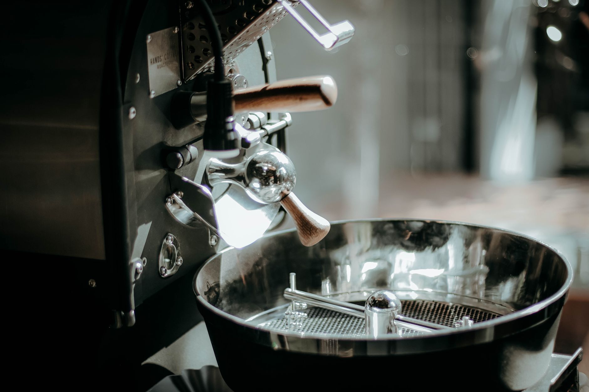 Close-up of a shiny industrial coffee roaster in a cafe setting, highlighting details.