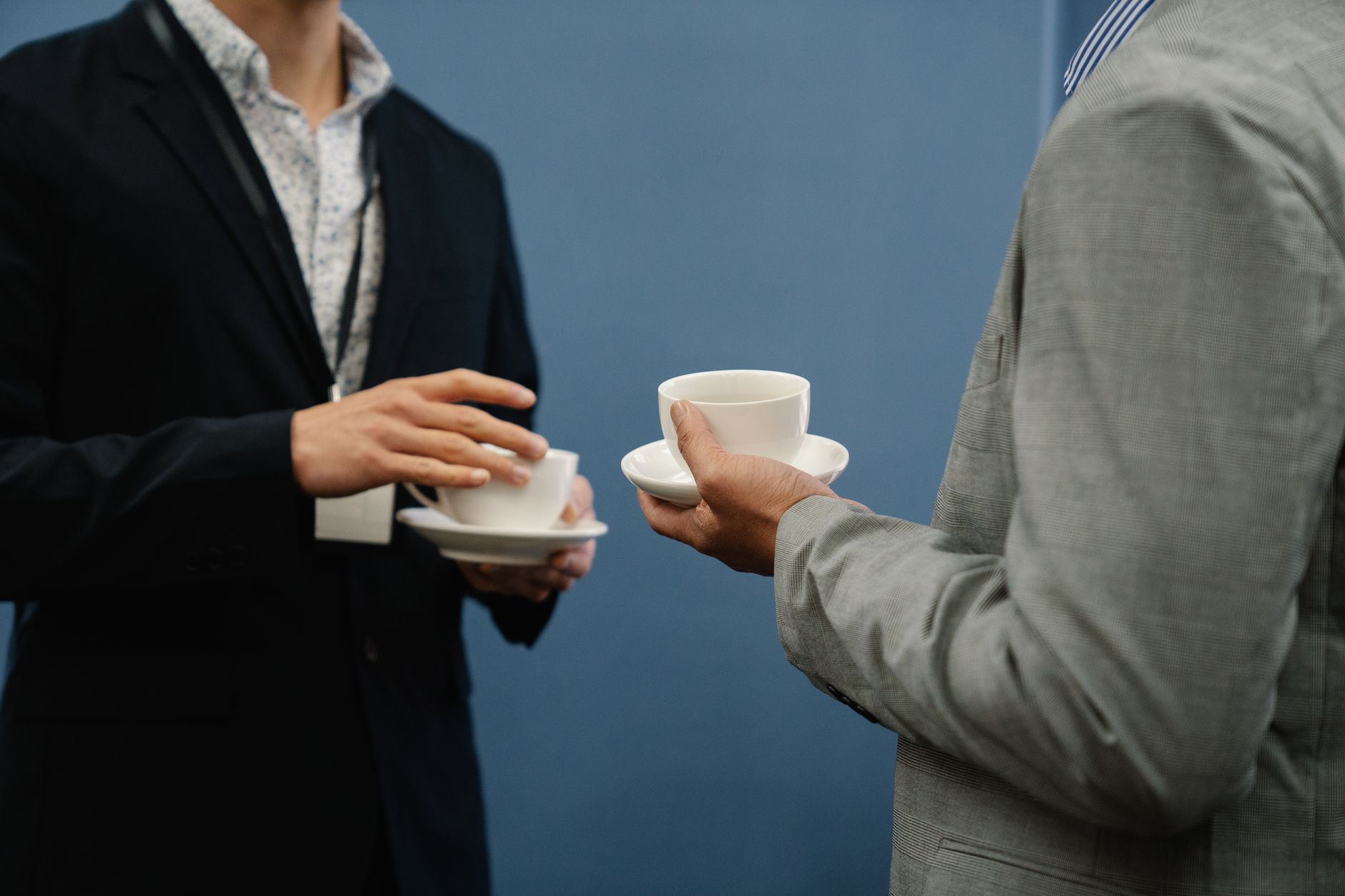 Two business professionals holding coffee cups during a casual meeting or event.