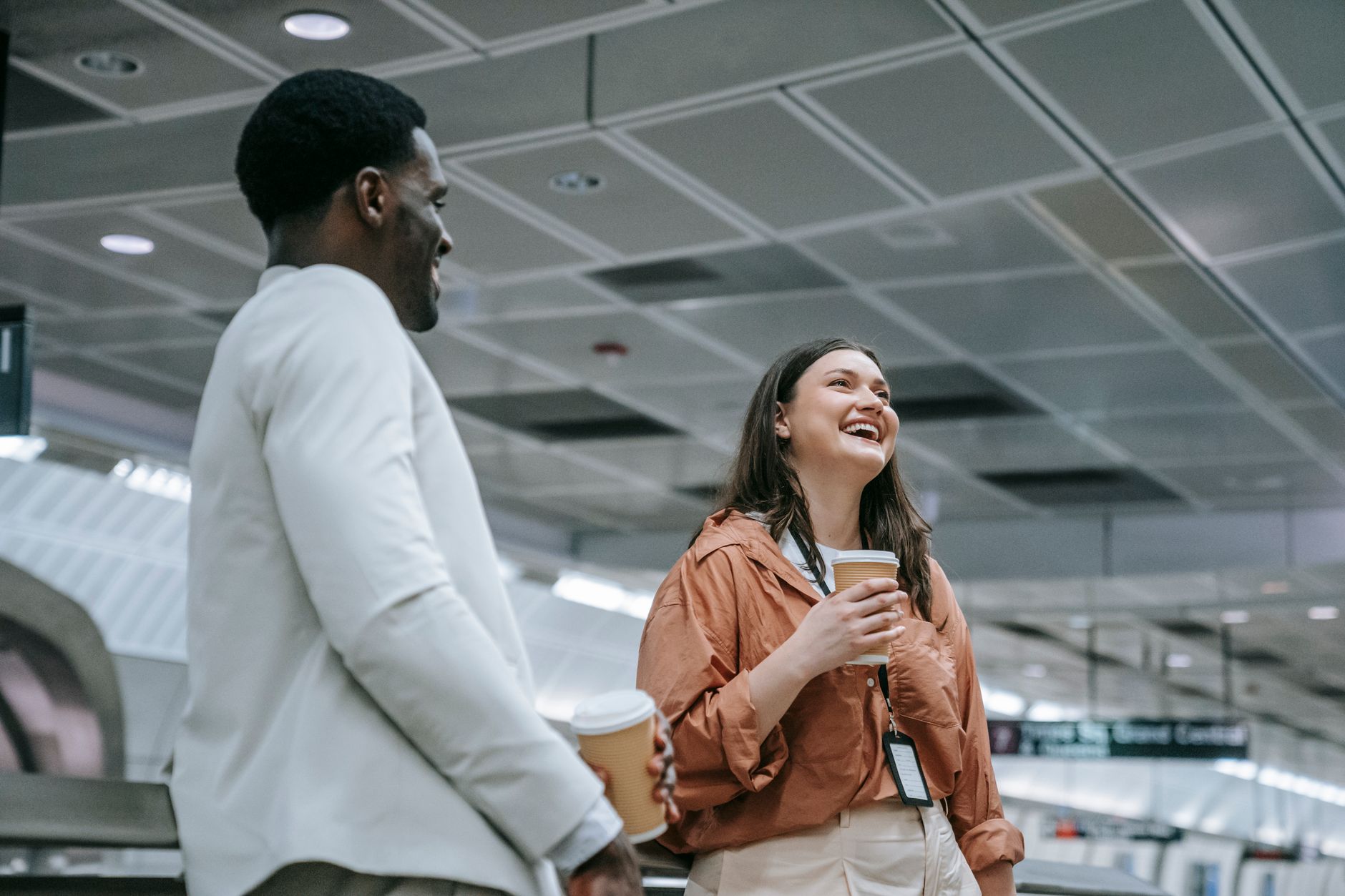 A joyful couple sharing a moment indoors, holding coffee cups and smiling warmly.