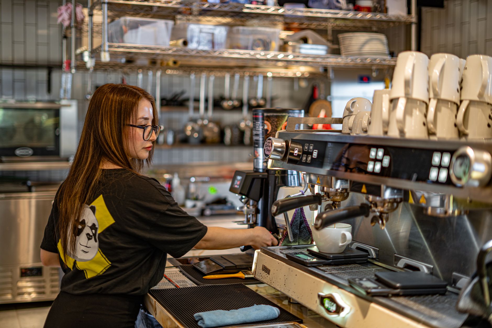 A barista making coffee with an espresso machine in a contemporary cafe setting.
